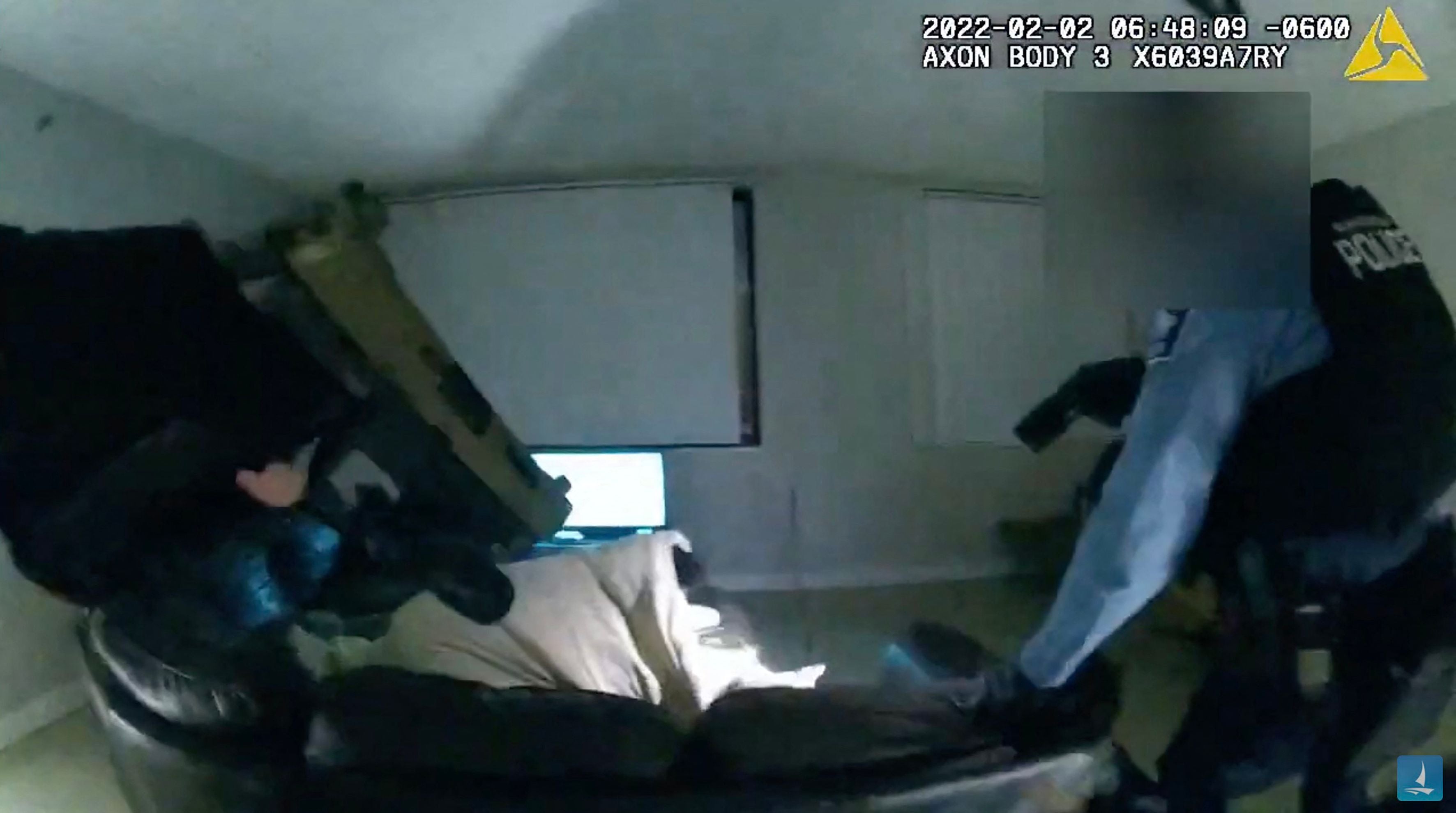 Police point their guns at Amir Locke as he lies on a sofa under a blanket before being shot