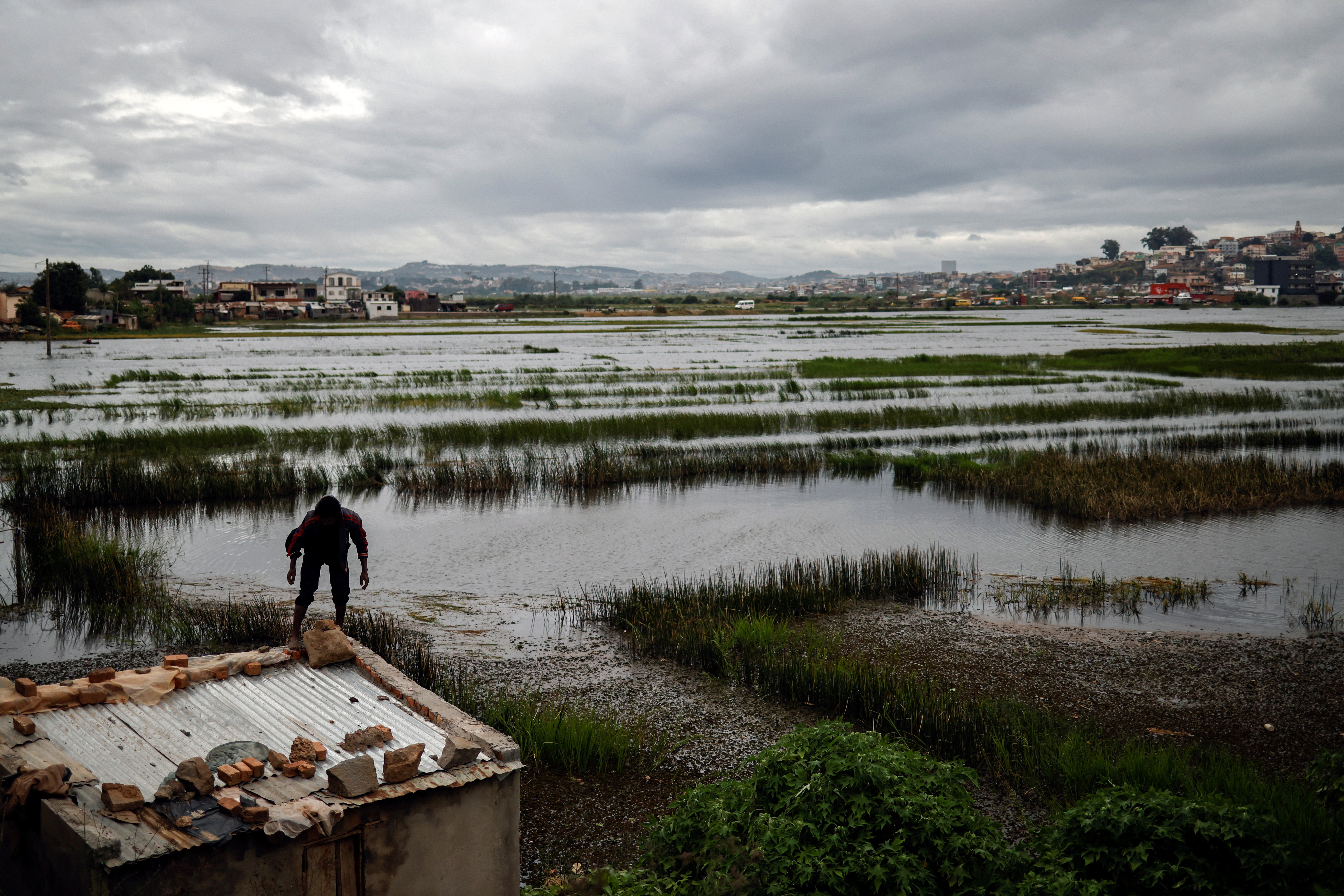 A man reinforces the roof of a house with rocks and sacks of sand, in the neighbourhood of Ambodimita, Madagascar