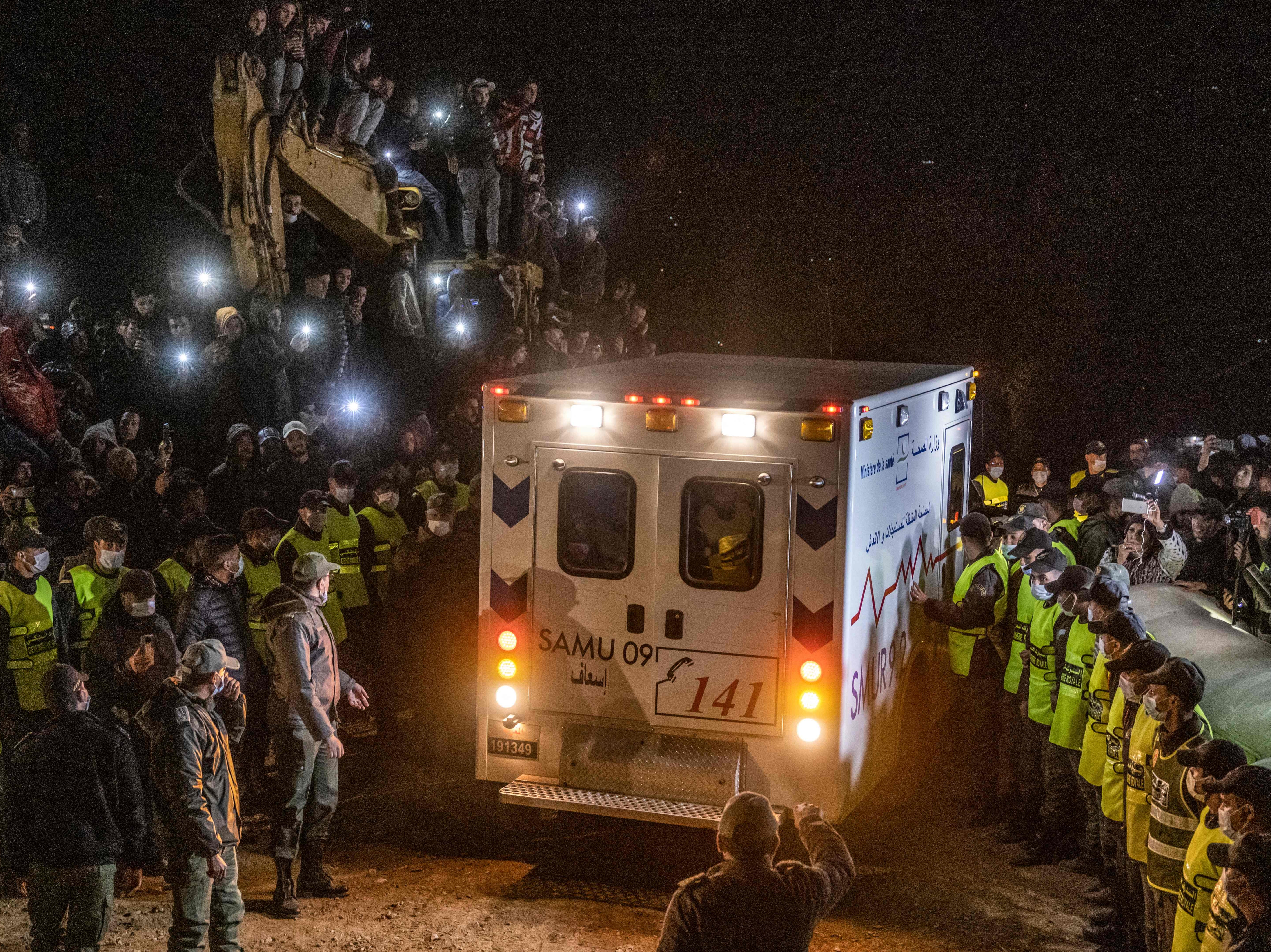 Moroccan security forces form a chain to contain the crowd as the ambulance carrying Rayan Oram leaves the scene