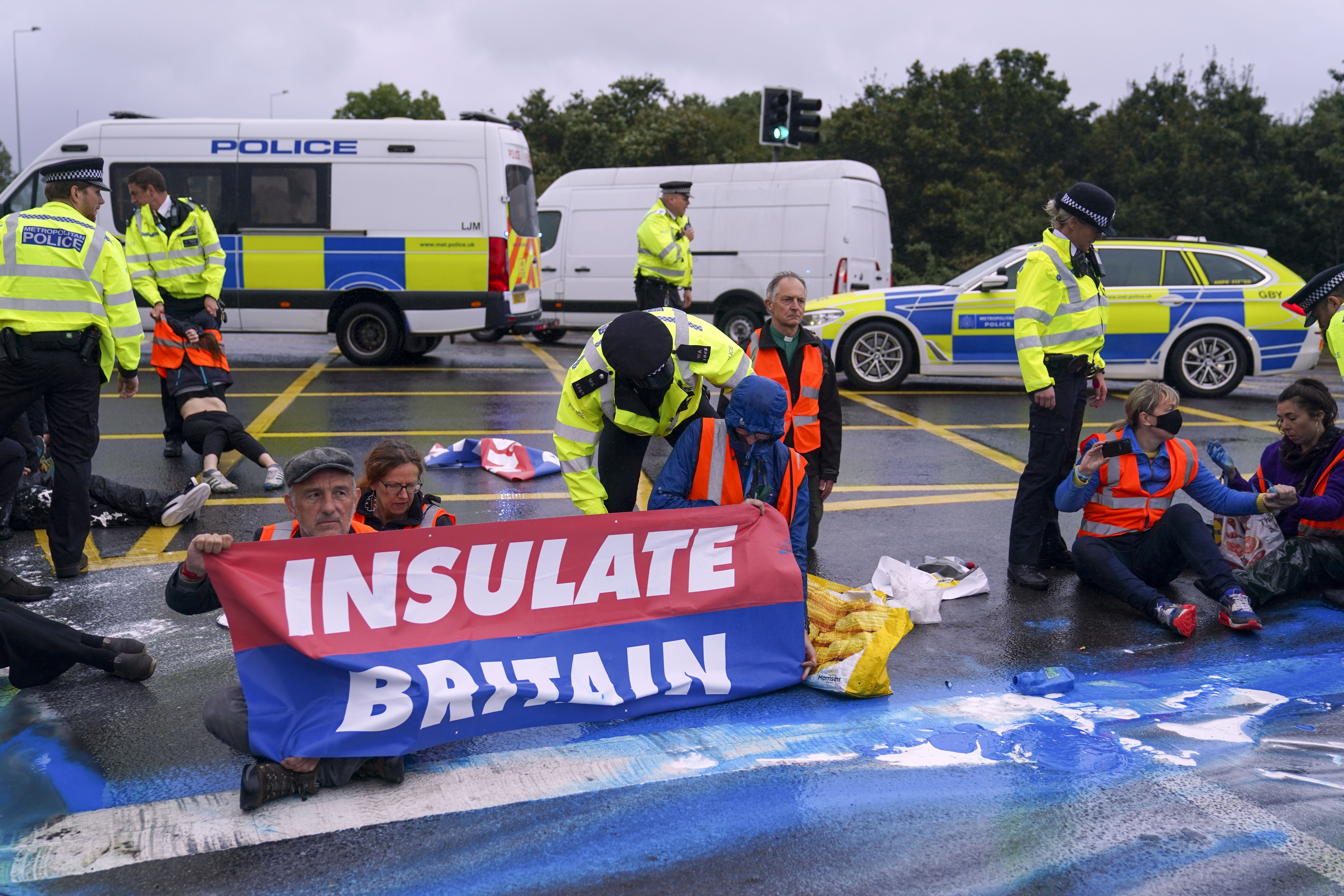 Police detain an Insulate Britain protester occupying a roundabout leading from the M25 motorway to Heathrow Airport in September 2021 (Steve Parsons/PA)