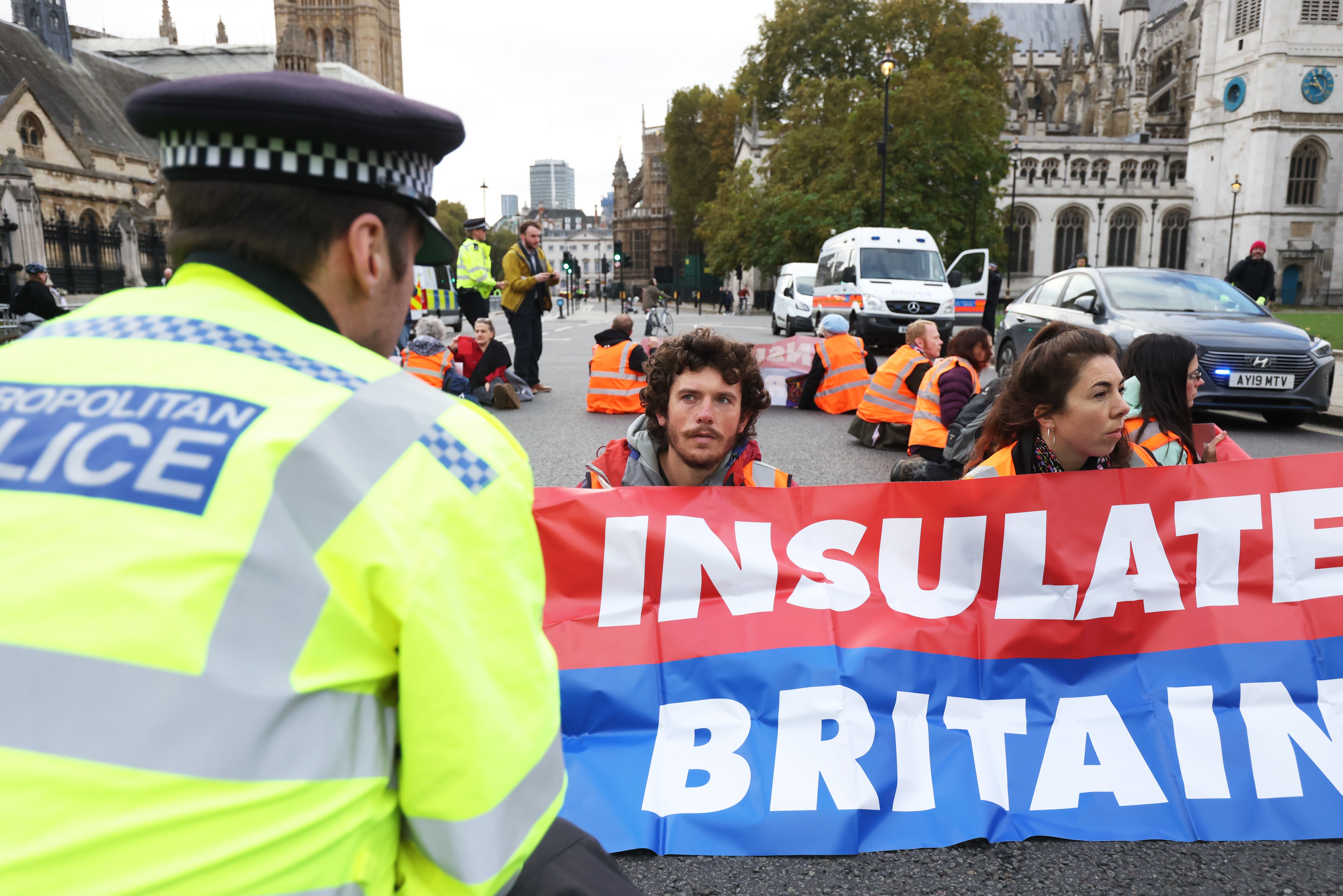 A police officer speaks to Insulate Britain activists as they block the road in Parliament Square (James Manning/PA)