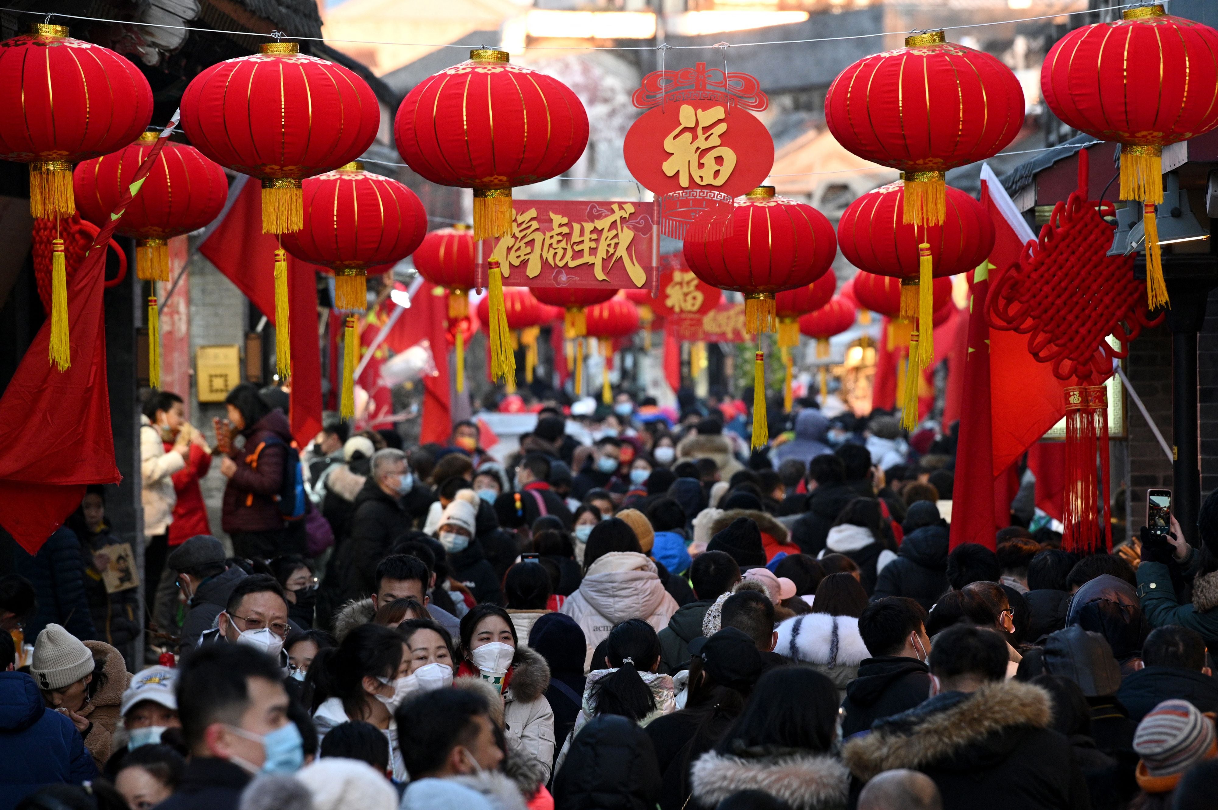 People walk through an alley decorated with traditional lanterns in Beijing, 2 February 2022