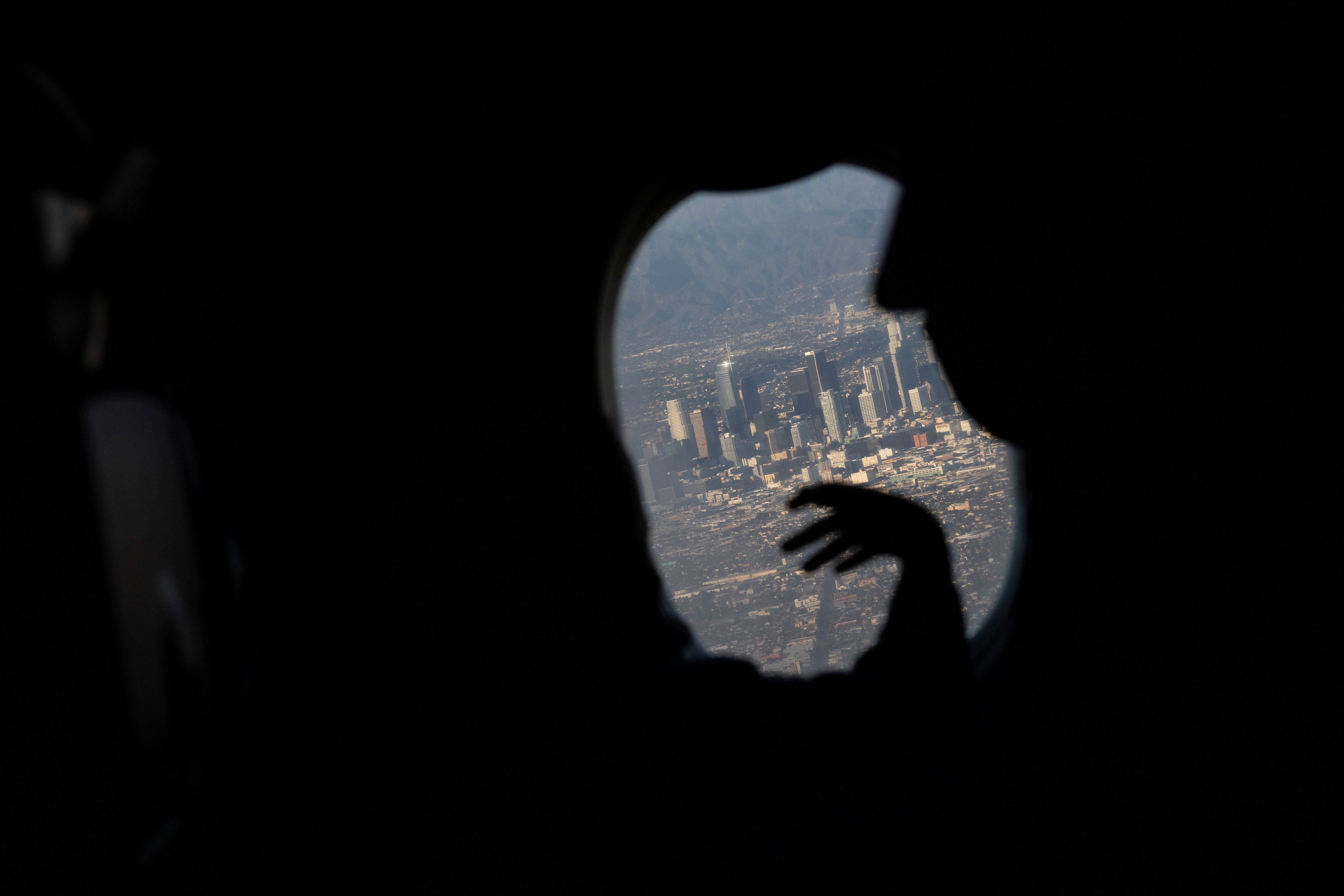 The family look out at the city of Los Angeles from an airplane window