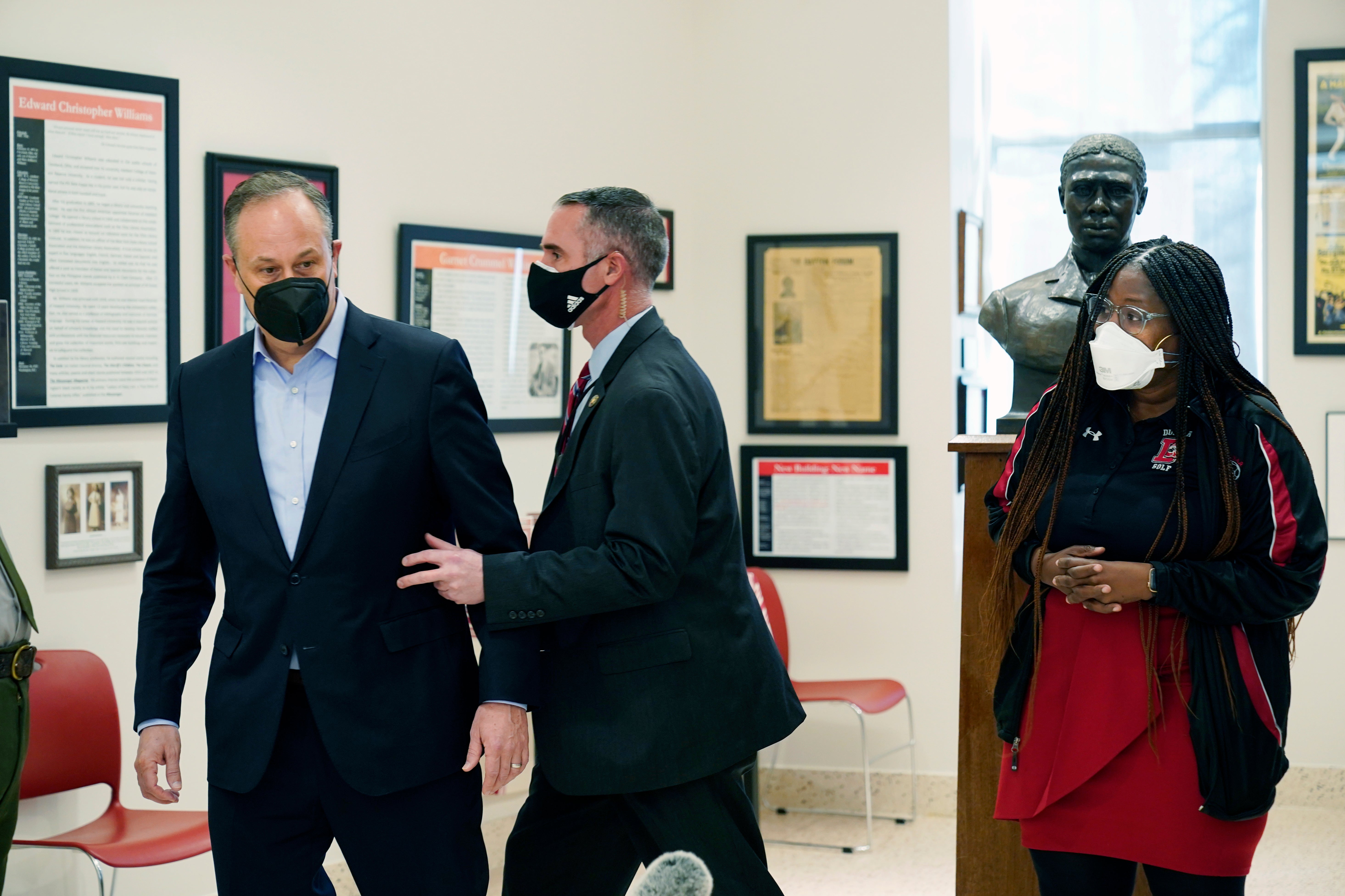 Doug Emhoff, the husband of Vice President Kamala Harris, is whisked out of an event at a high school by a Secret Service agent following an apparent security concern, Tuesday, Feb. 8, 2022 in Washington. On the far right is Nadine Smith, Dunbar principal. (AP Photo/Manuel Balce Ceneta)