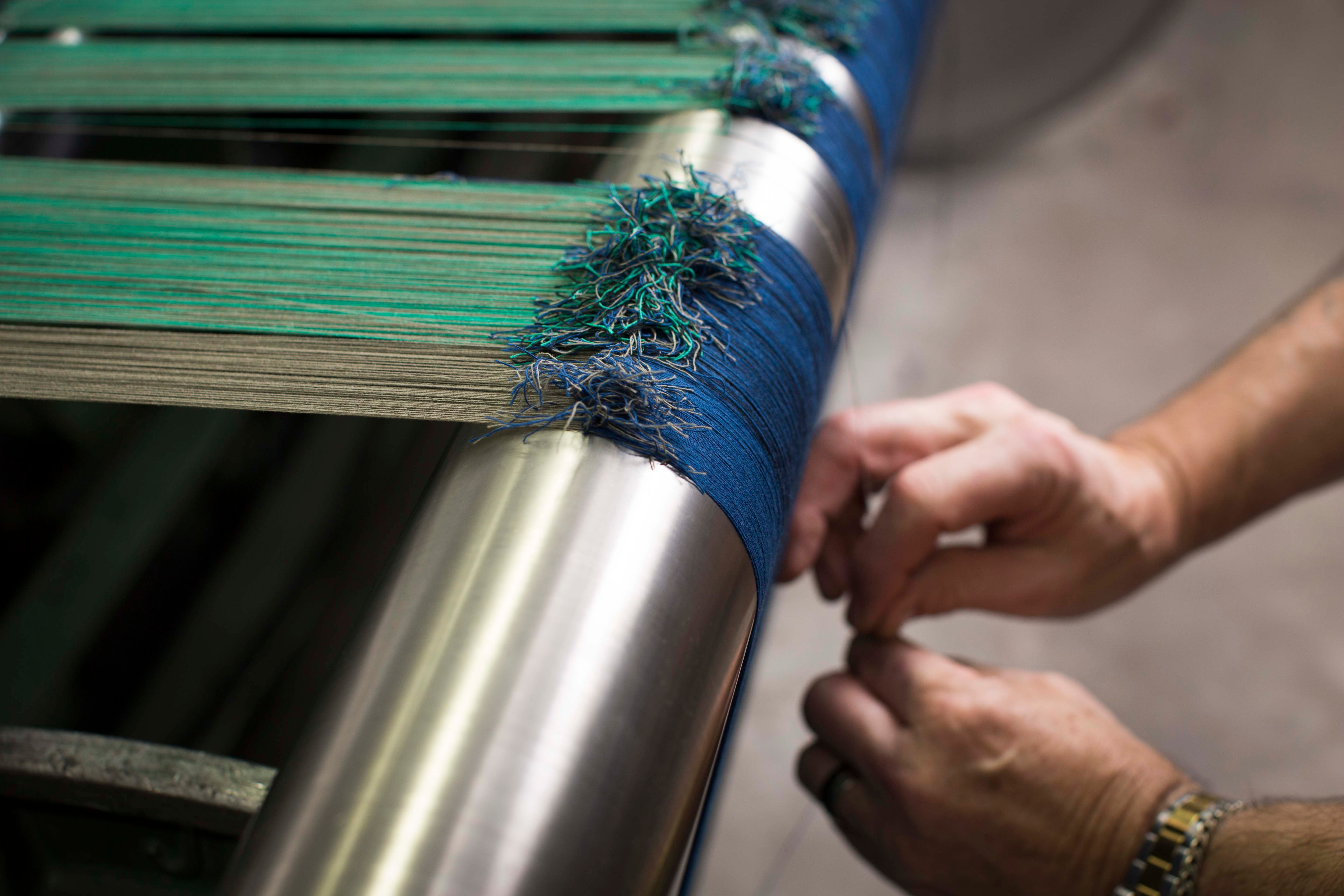 A weaver sets up the loom by hand, ready to create a garment. Each piece is then fully fashioned; knitted to shape for the best fit