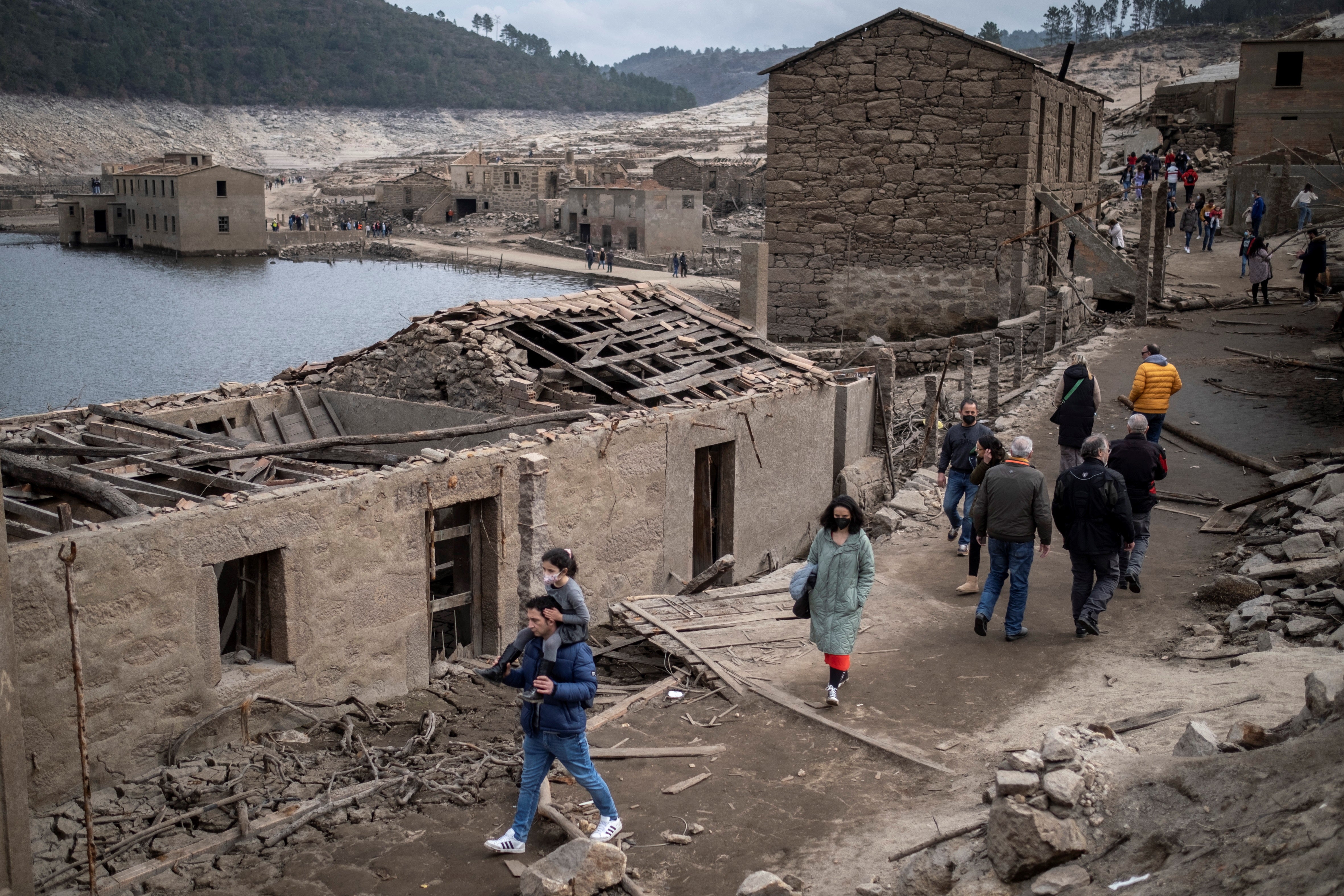 People walk among damaged buildings in the abandoned village of Aceredo, which was was flooded in 1992 as part of a hydro-electric power project but has emerged as a consequence of the ongoing drought