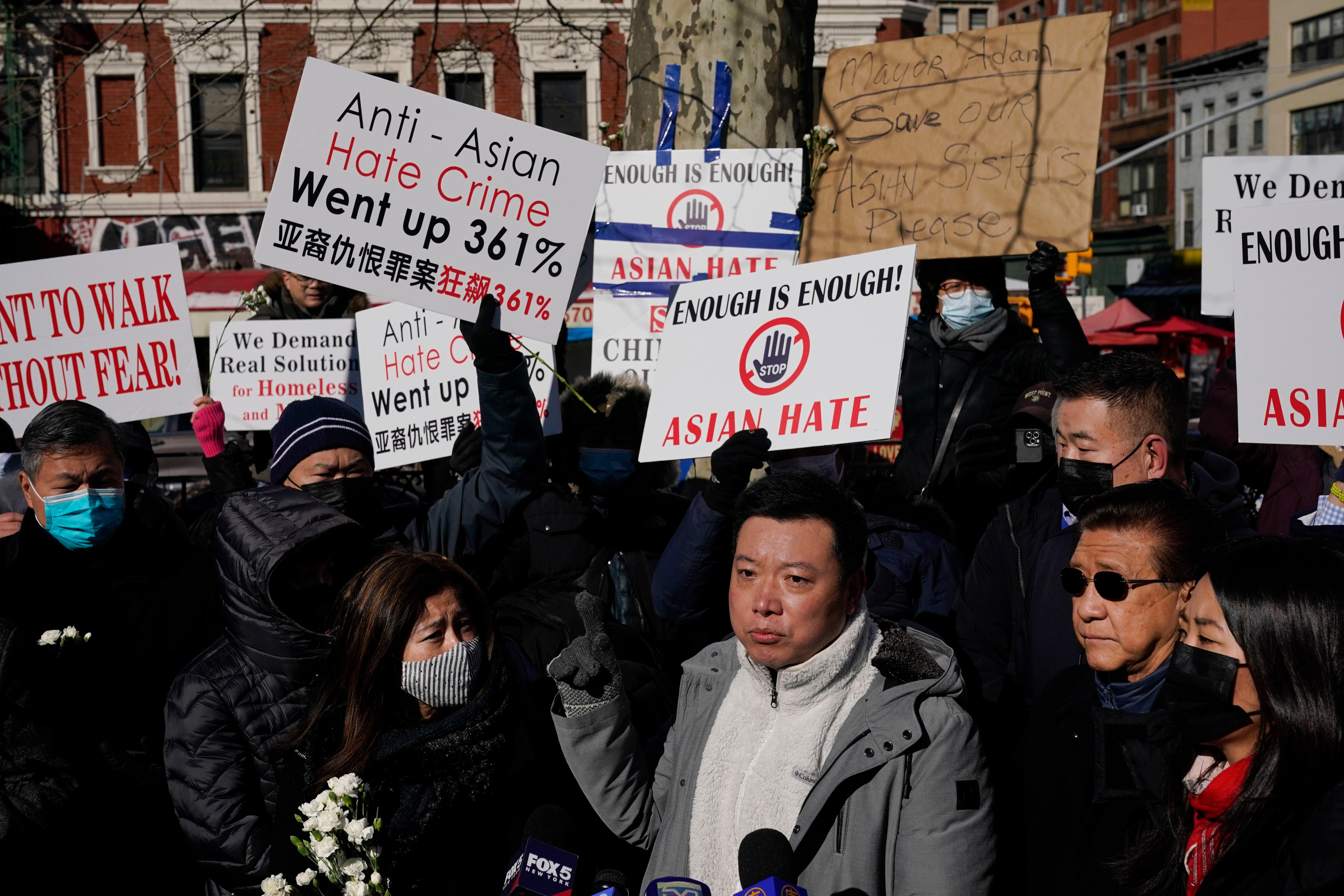 Mourners hold signs demanding an end to anti-Asian attacks at a vigil for Lee