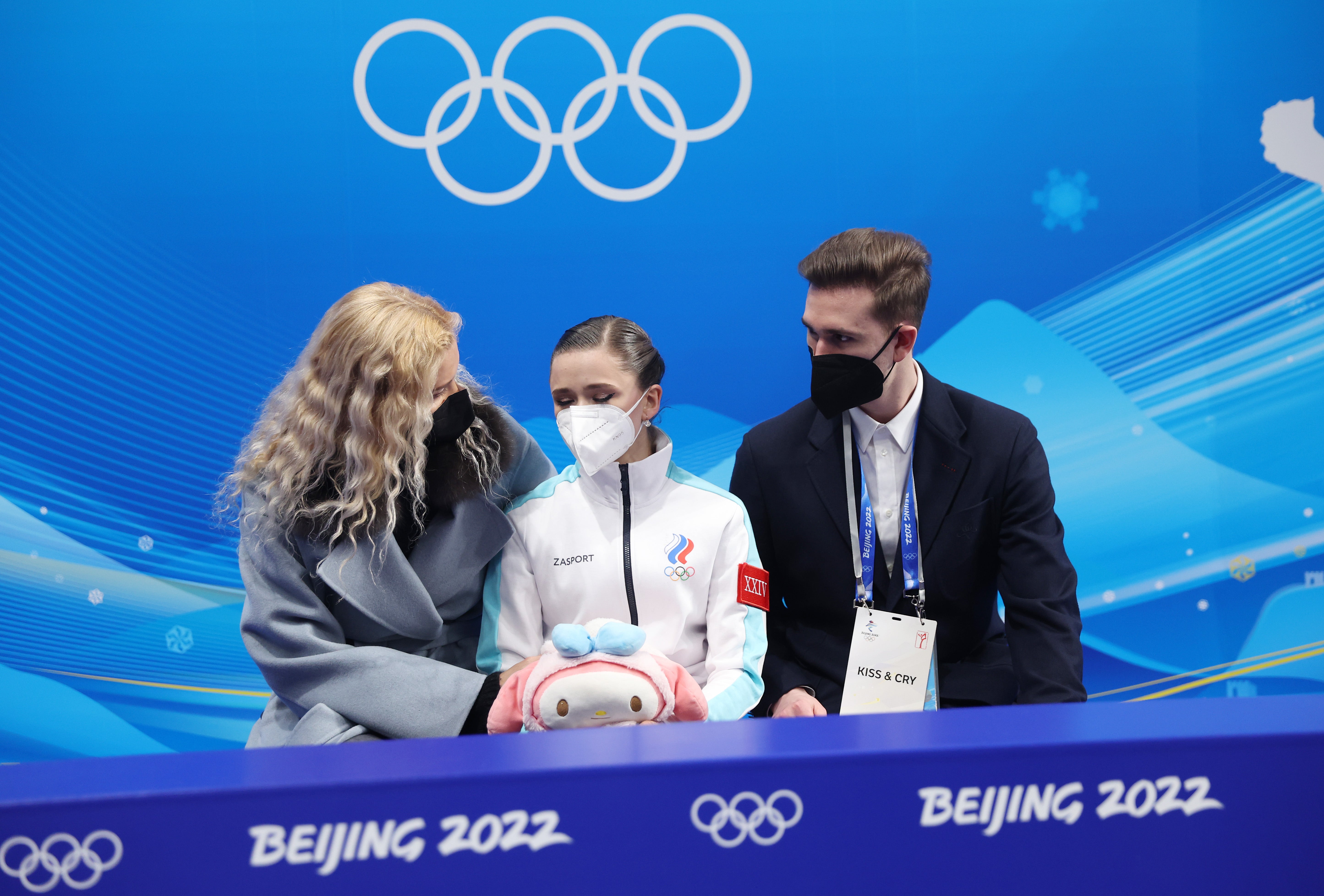 Kamila Valieva of Team ROC waits for their score with choreographer Daniil Gleikhengauz (R) and coach Eteri Tutberidze