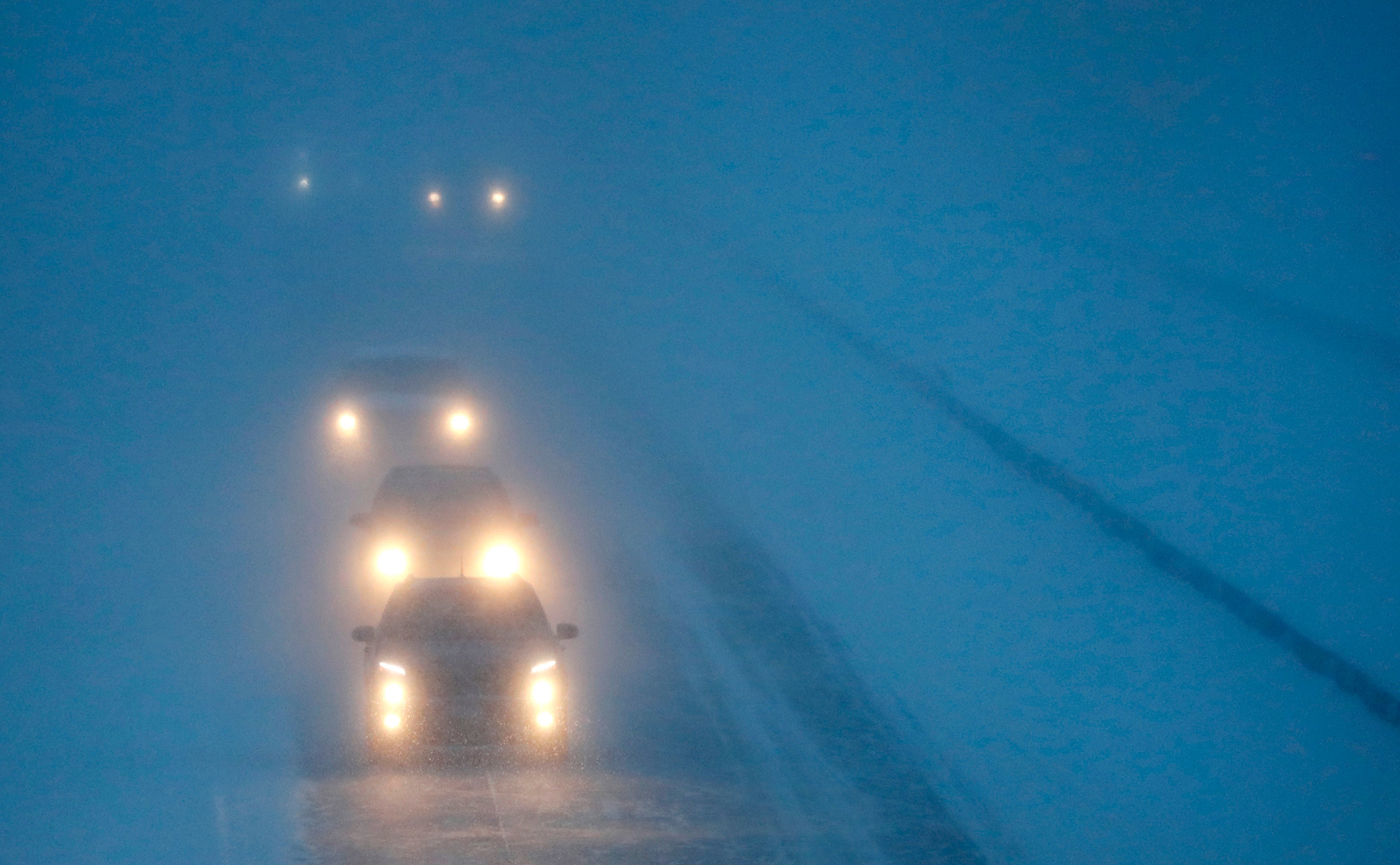 Headlights from morning commuters can be seen through blowing snow