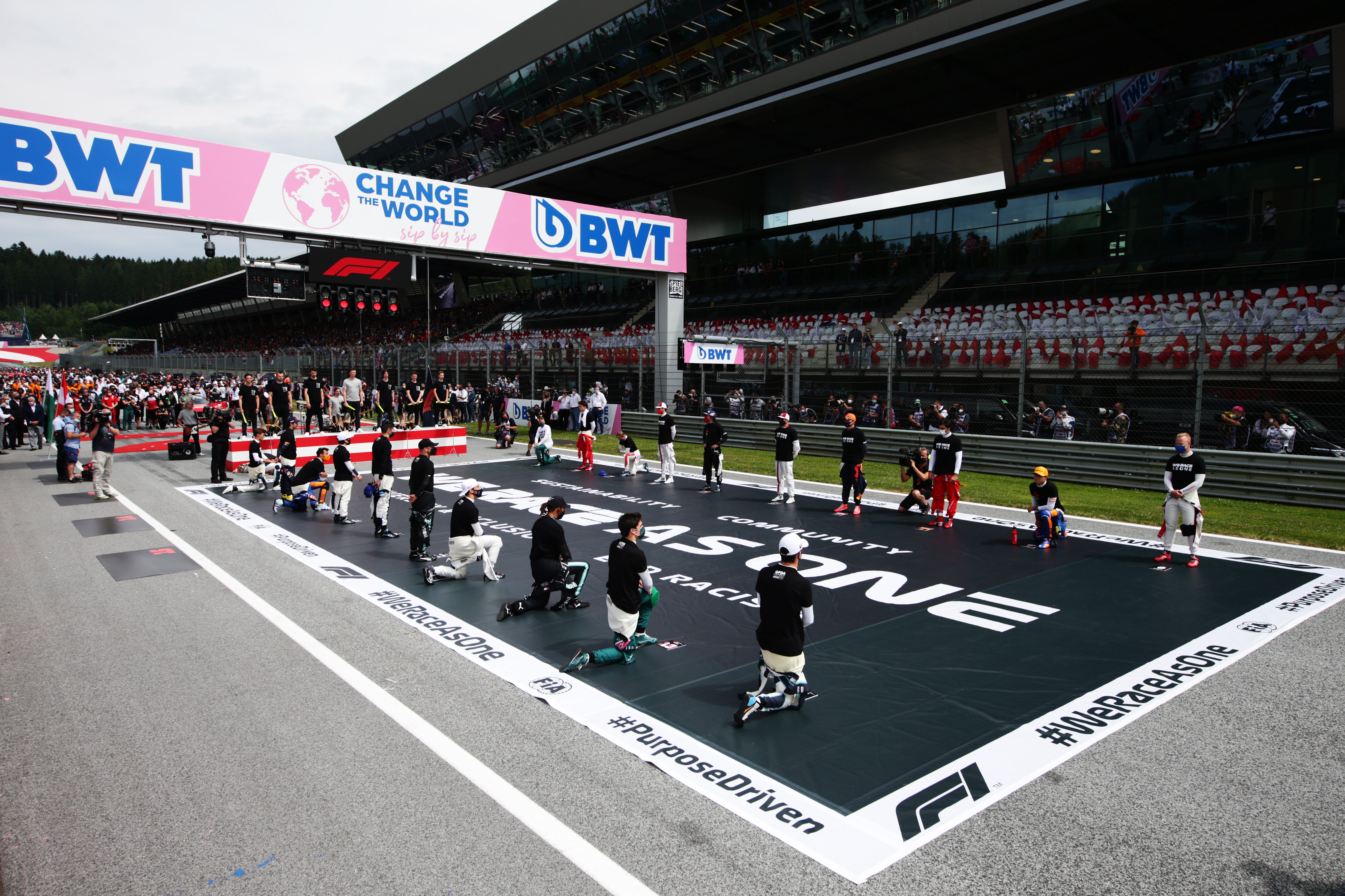 The drivers stand and kneel on the grid in support of the We Race As One campaign before the Austrian Grand Prix