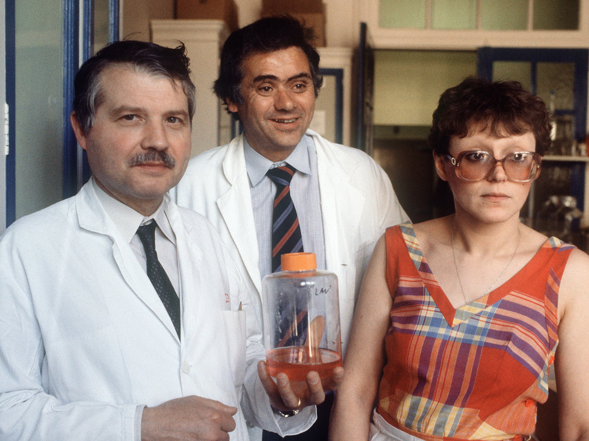 Montagnier (left), Jean-Claude Chermann (centre) and Françoise Barré-Sinoussi pose with a jar containing the lymphadenopathy associated virus in 1984