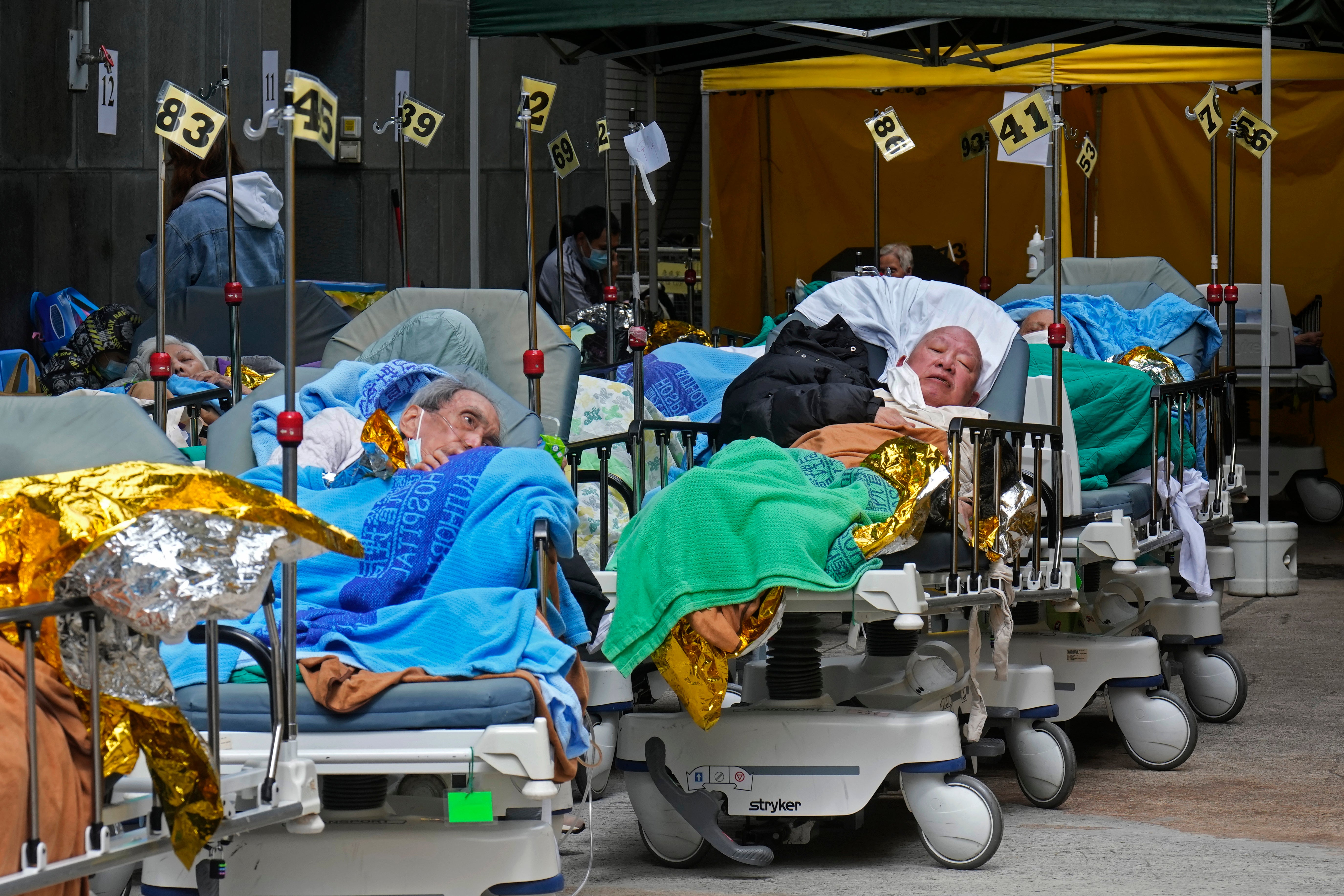 Patients lie on hospital beds as they wait at a temporary holding area outside Caritas Medical Centre in Hong Kong