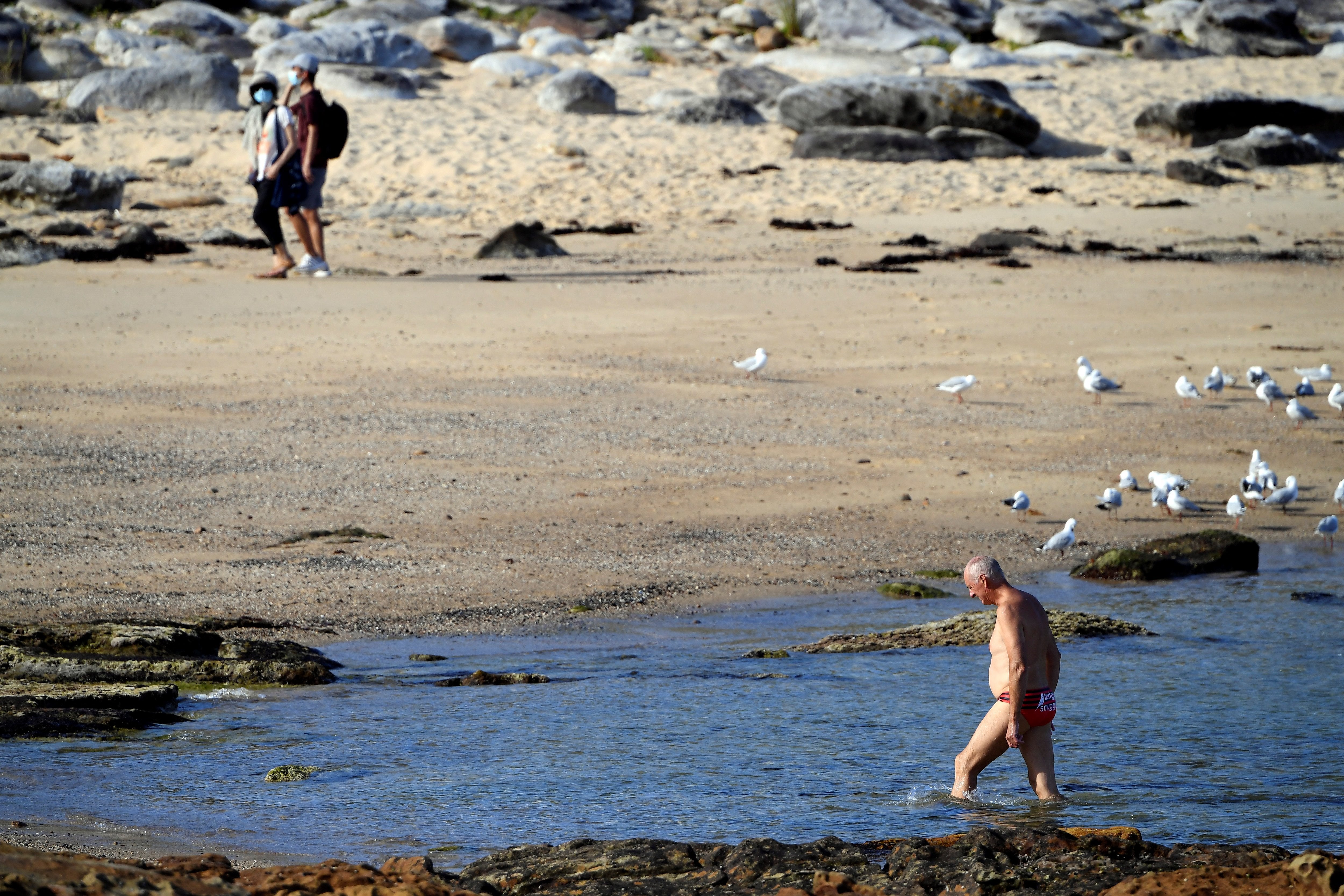 People walk close to the site of a fatal shark attack off Little Bay Beach in Sydney on 17 February 2022, as authorities deployed baited lines to try to catch a giant great white shark