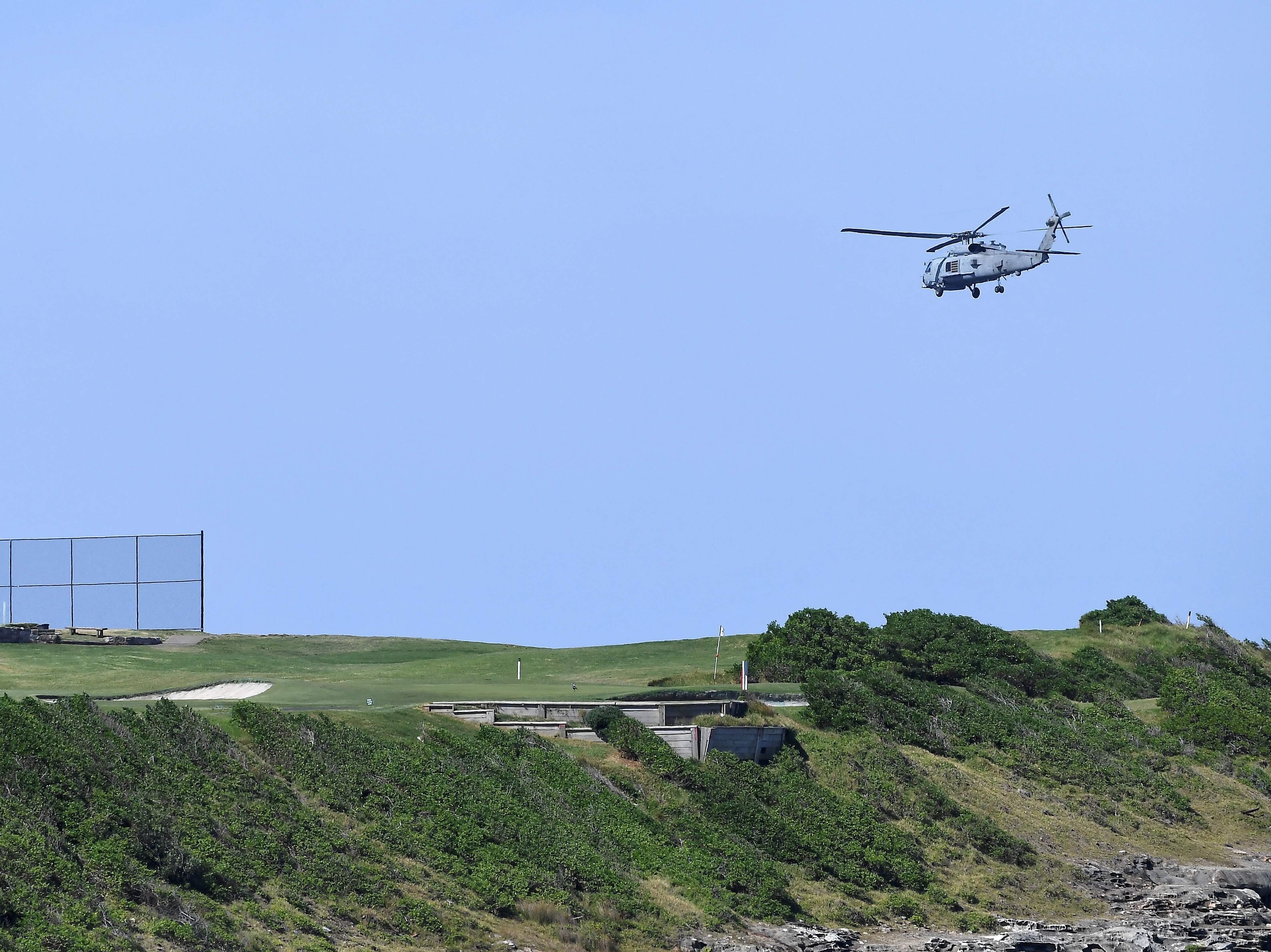 A navy helicopter hovers above the fatal shark attack site on Little Bay in Sydney as authorities deployed baited lines to try to catch the great white shark