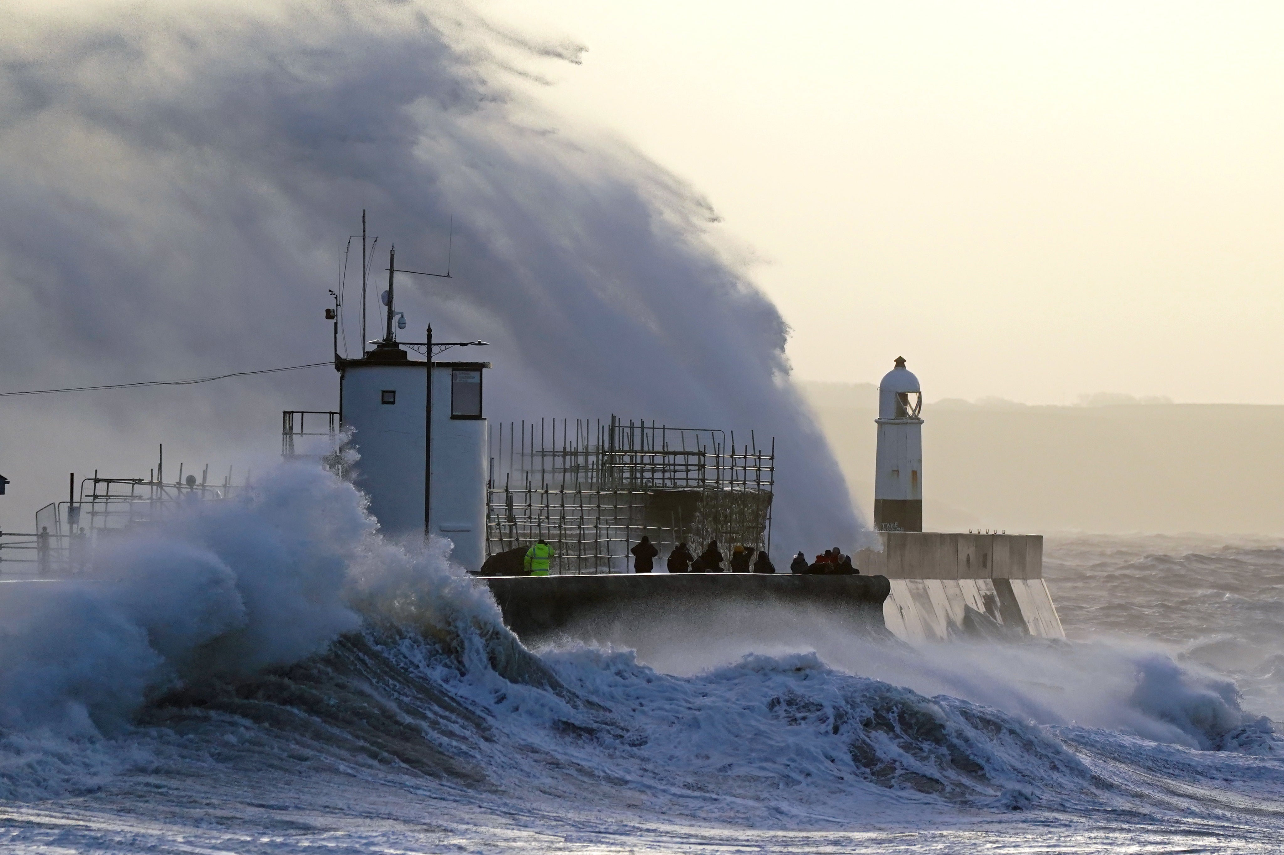 Waves crash against the sea wall and Porthcawl Lighthouse in Porthcawl, Wales (Jacob King/PA)