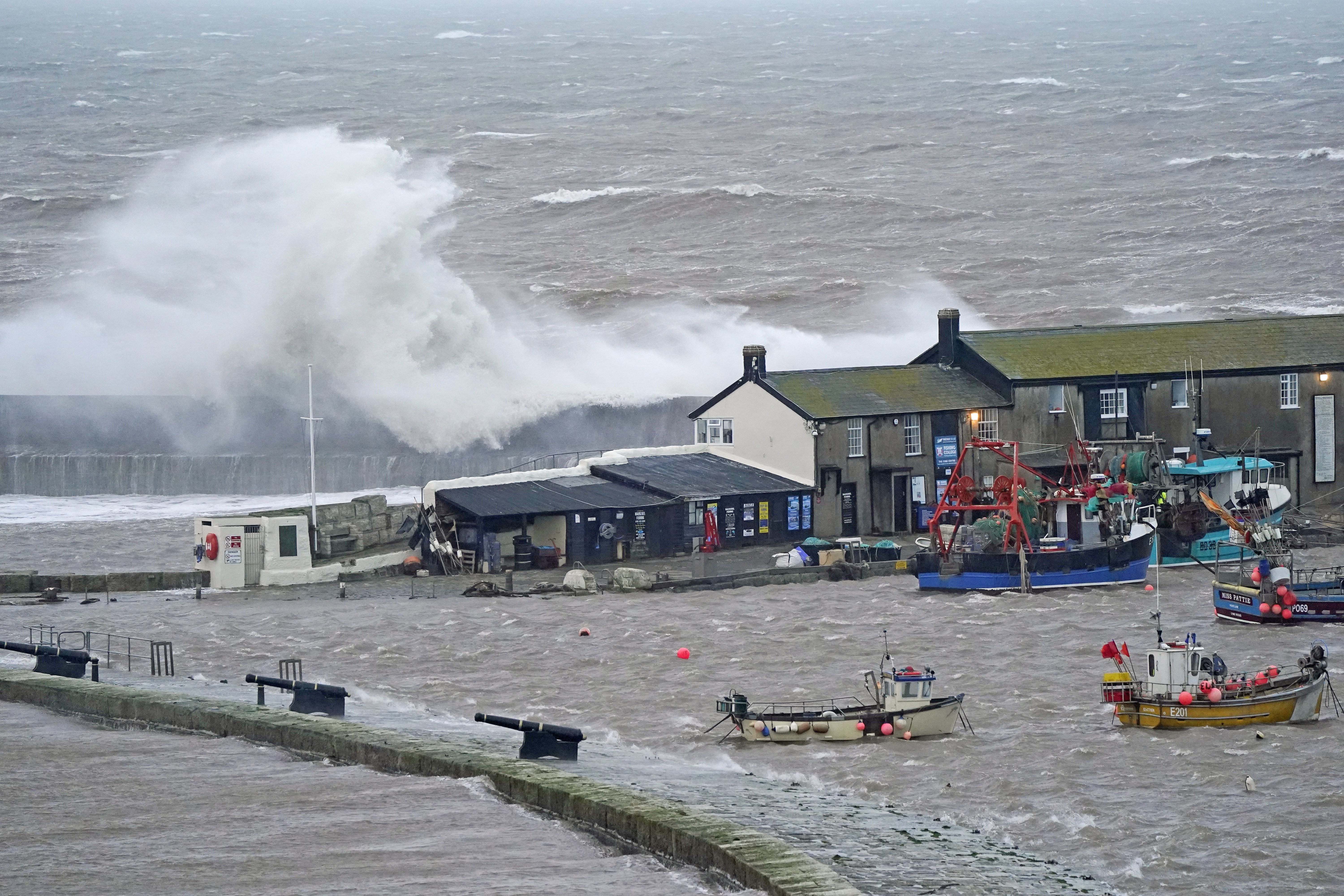 Waves crash over the sea wall at the harbour in Lyme Regis in Dorset