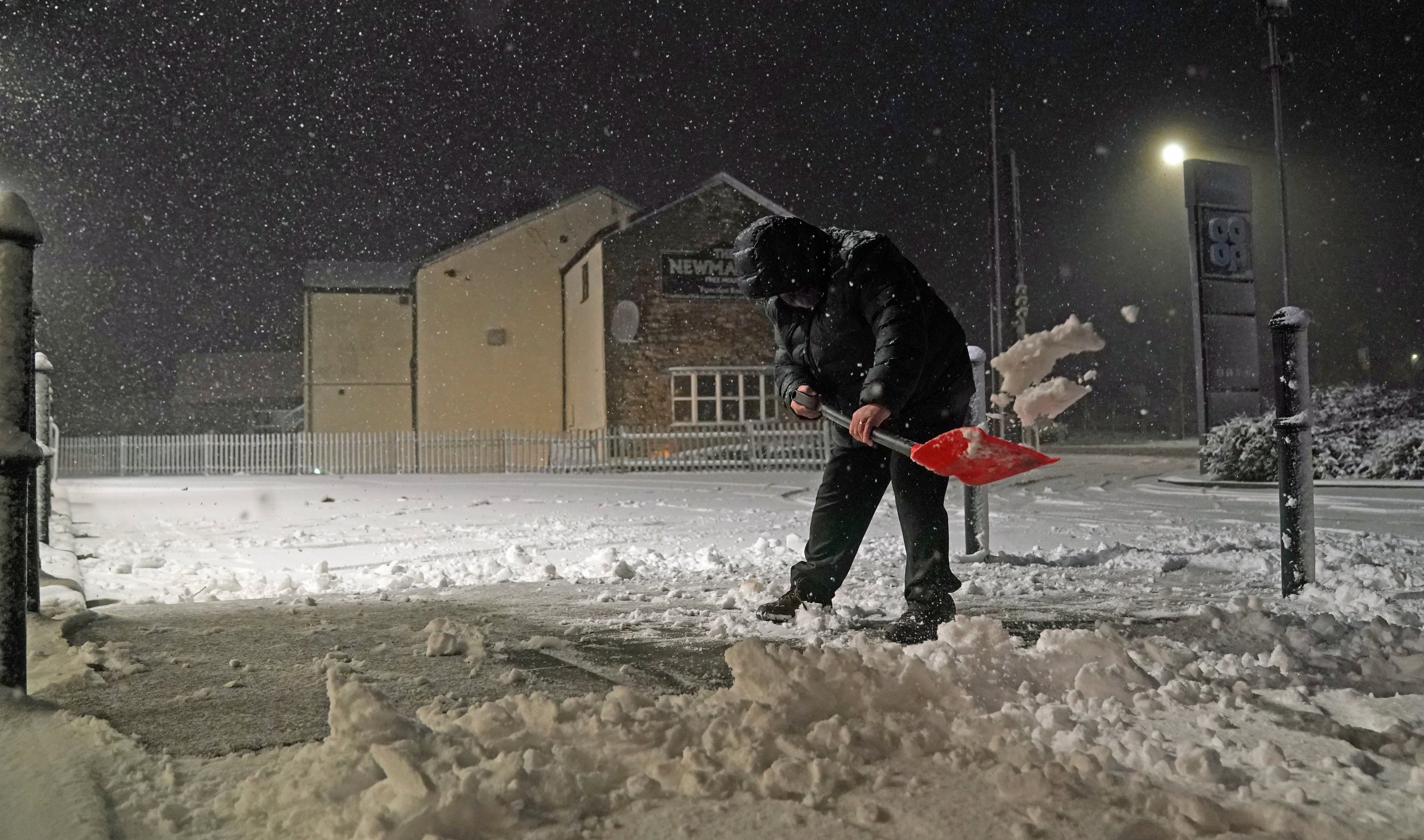 A person clears snow in Tow Law, County Durham, as Storm Eunice sweeps across the UK