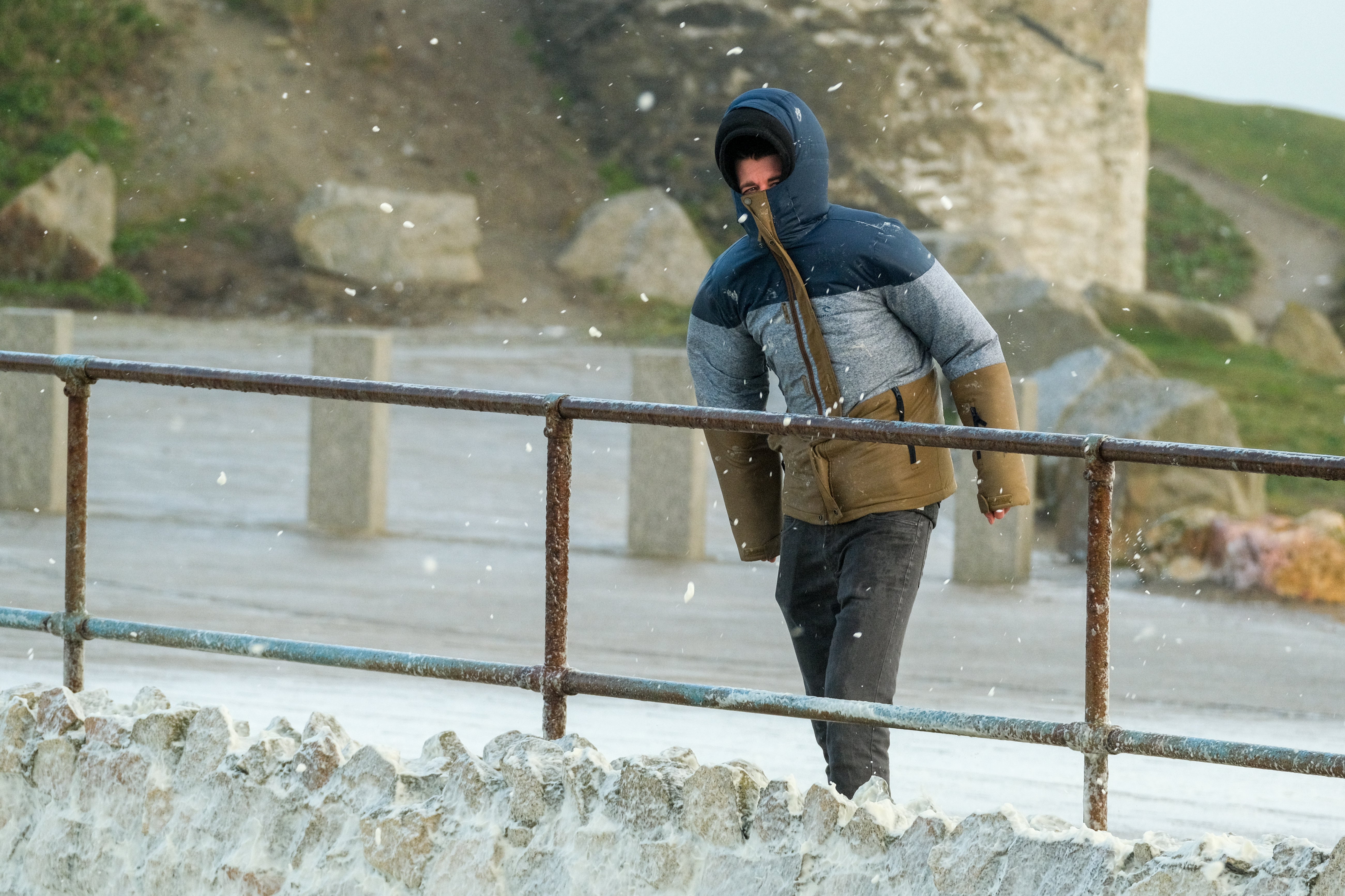 A man walks in high winds along the seafront in Newquay on the Cornish coast as Storm Eunice makes landfall