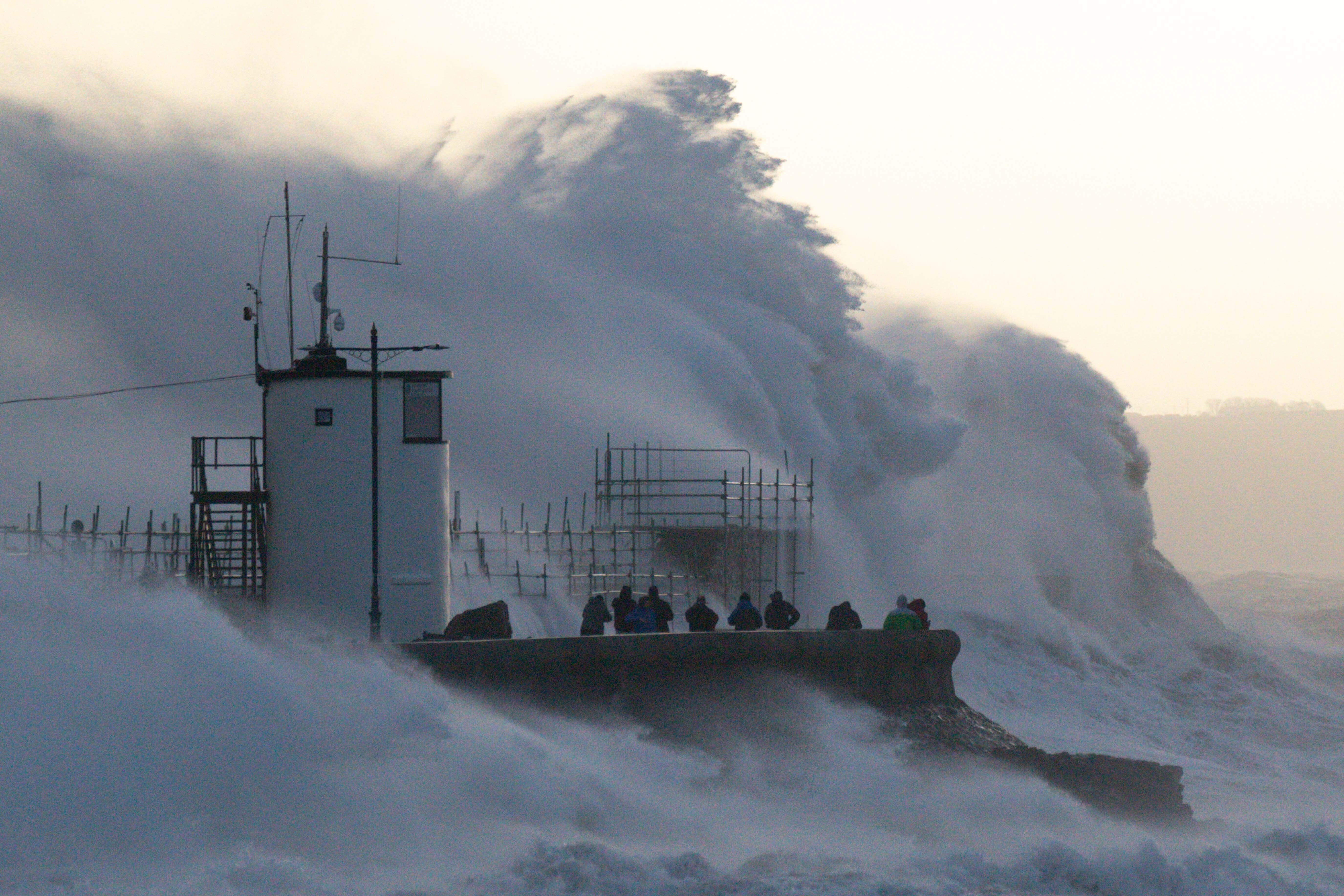 Waves crash against the sea wall and Porthcawl Lighthouse in Bridgend, Wales, during Storm Eunice (Jacob King/PA)