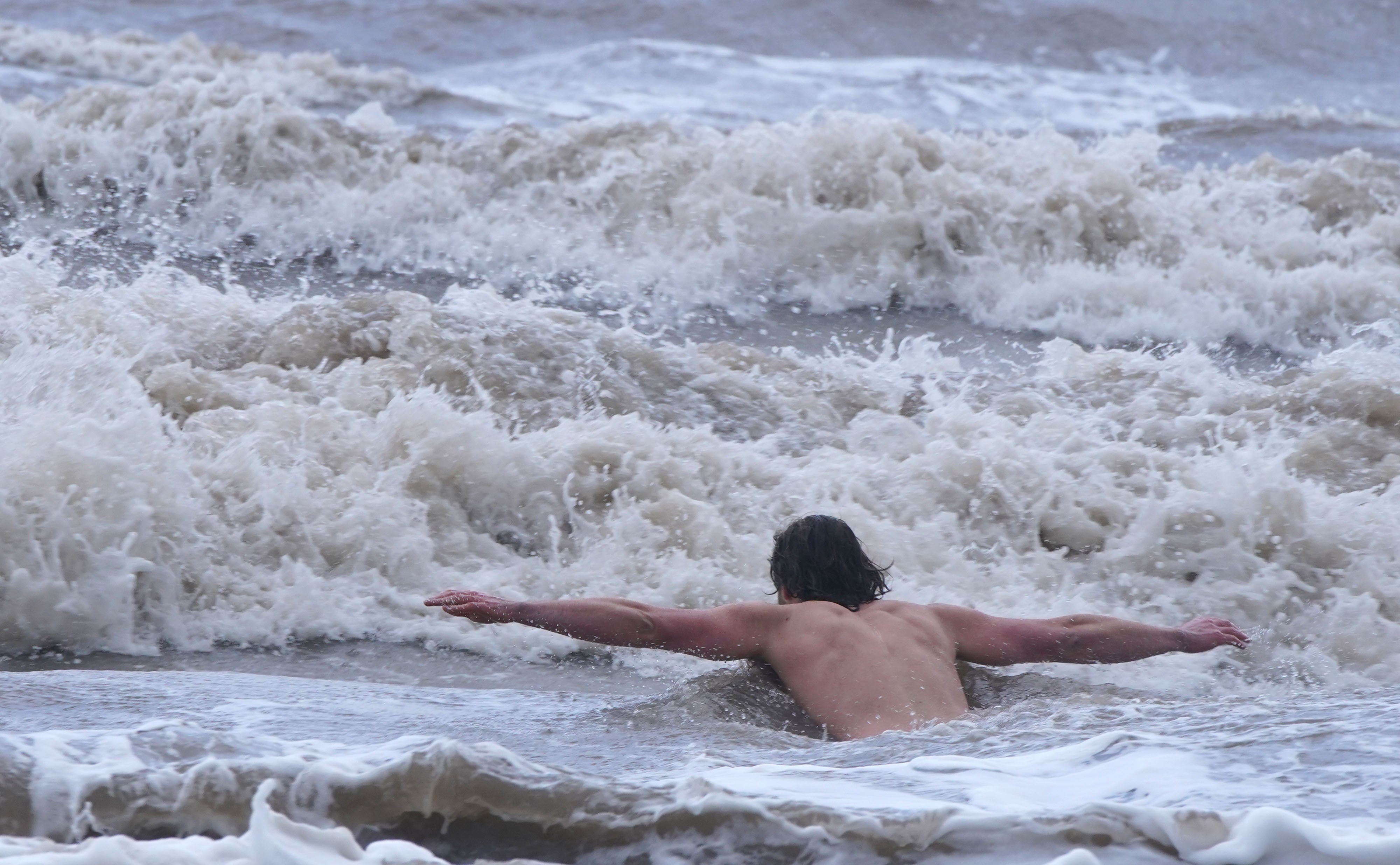 Storm Eunice: A man in New Brighton, Merseyside, swimming despite the weather warnings