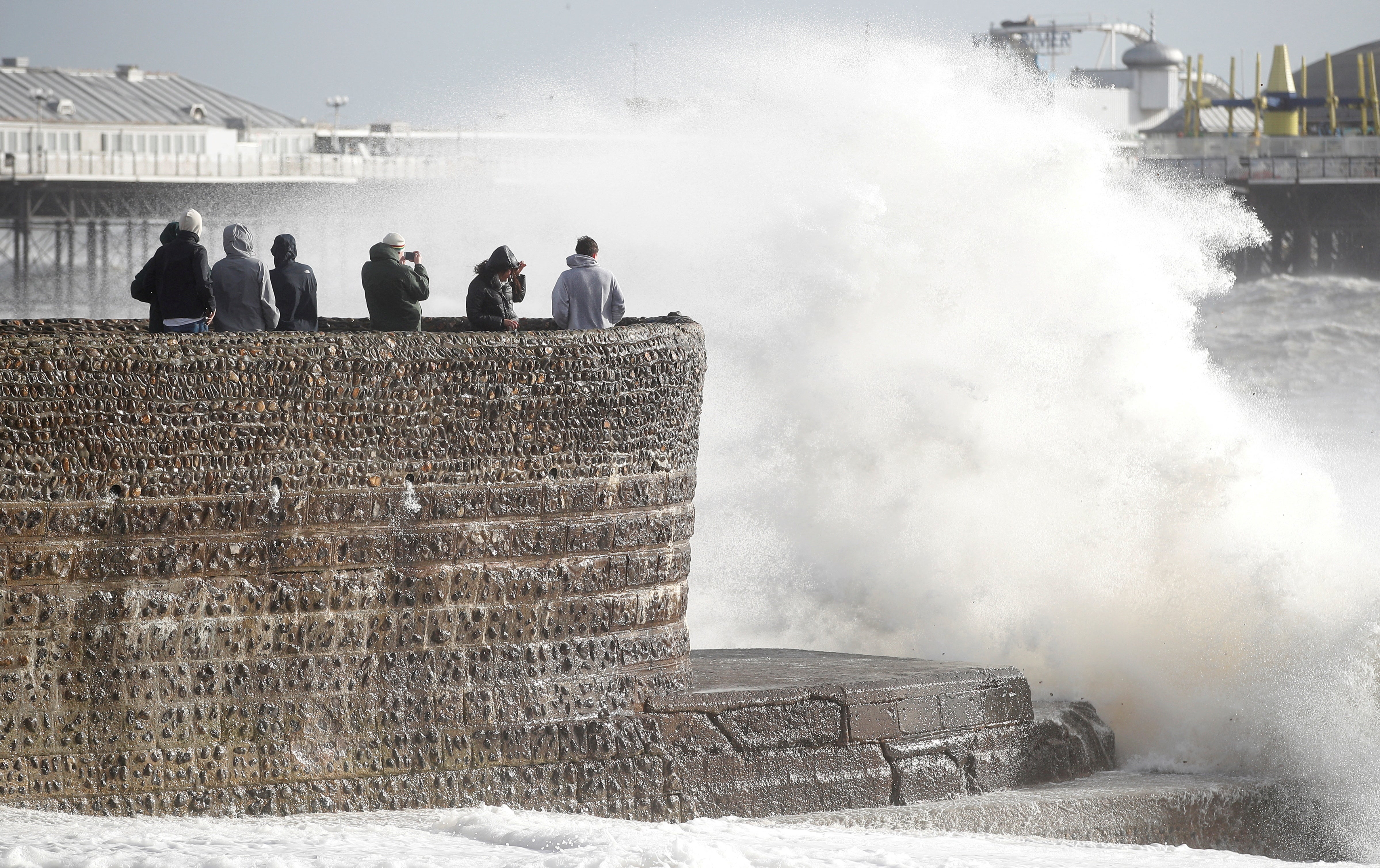 People take pictures as waves break on during Storm Eunice in Brighton