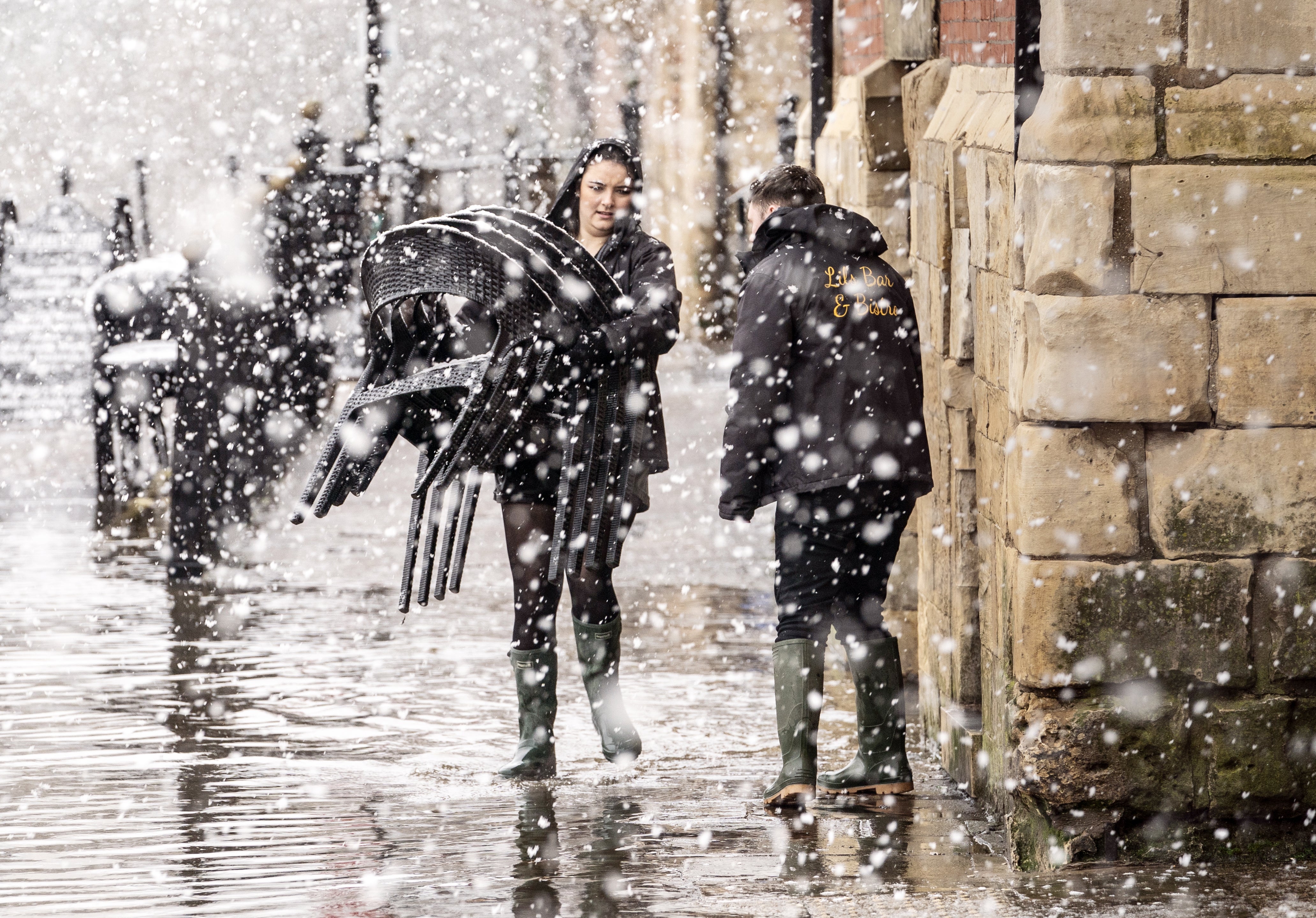 Pub staff move chairs through flood water and snow