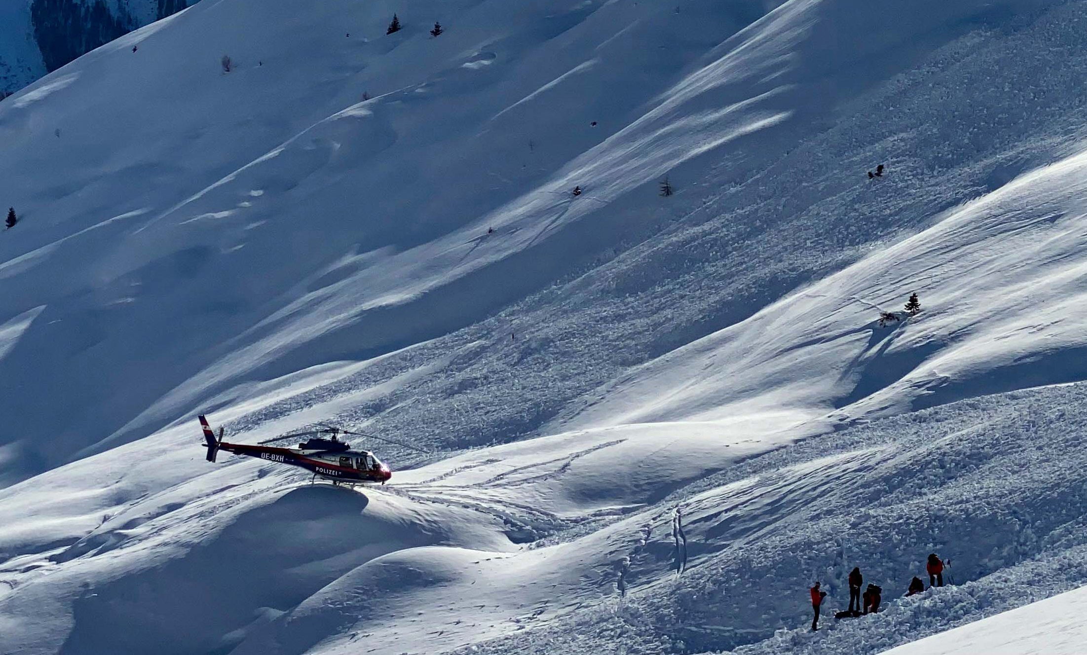 A police helicopter and emergency teams work at the site of an avalanche in the Spiss municipality, Austria, 4 February 2022