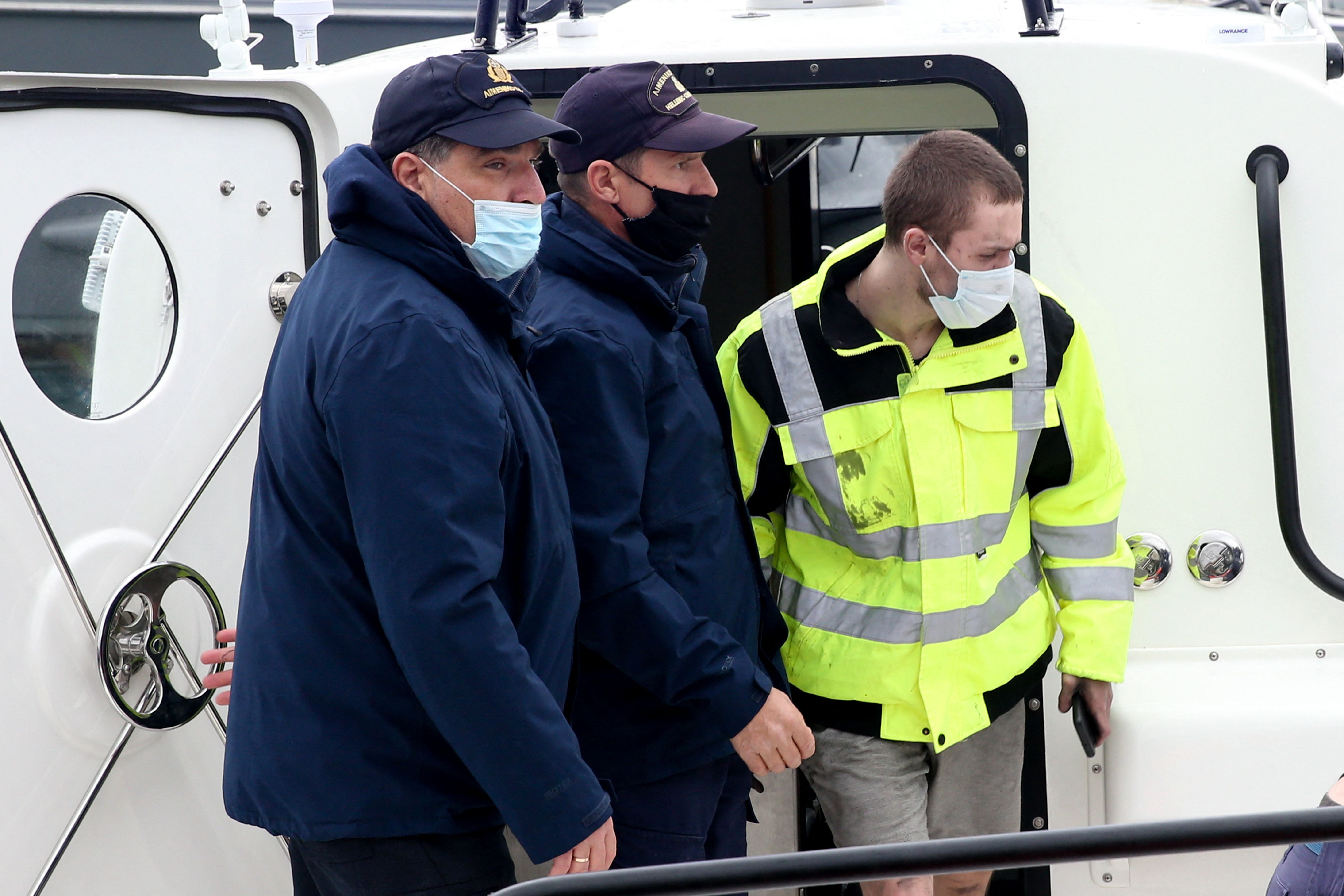 The Belarus survivor (R), 21, is escorted by Greek coast guards upon his arrival at the port of Corfu