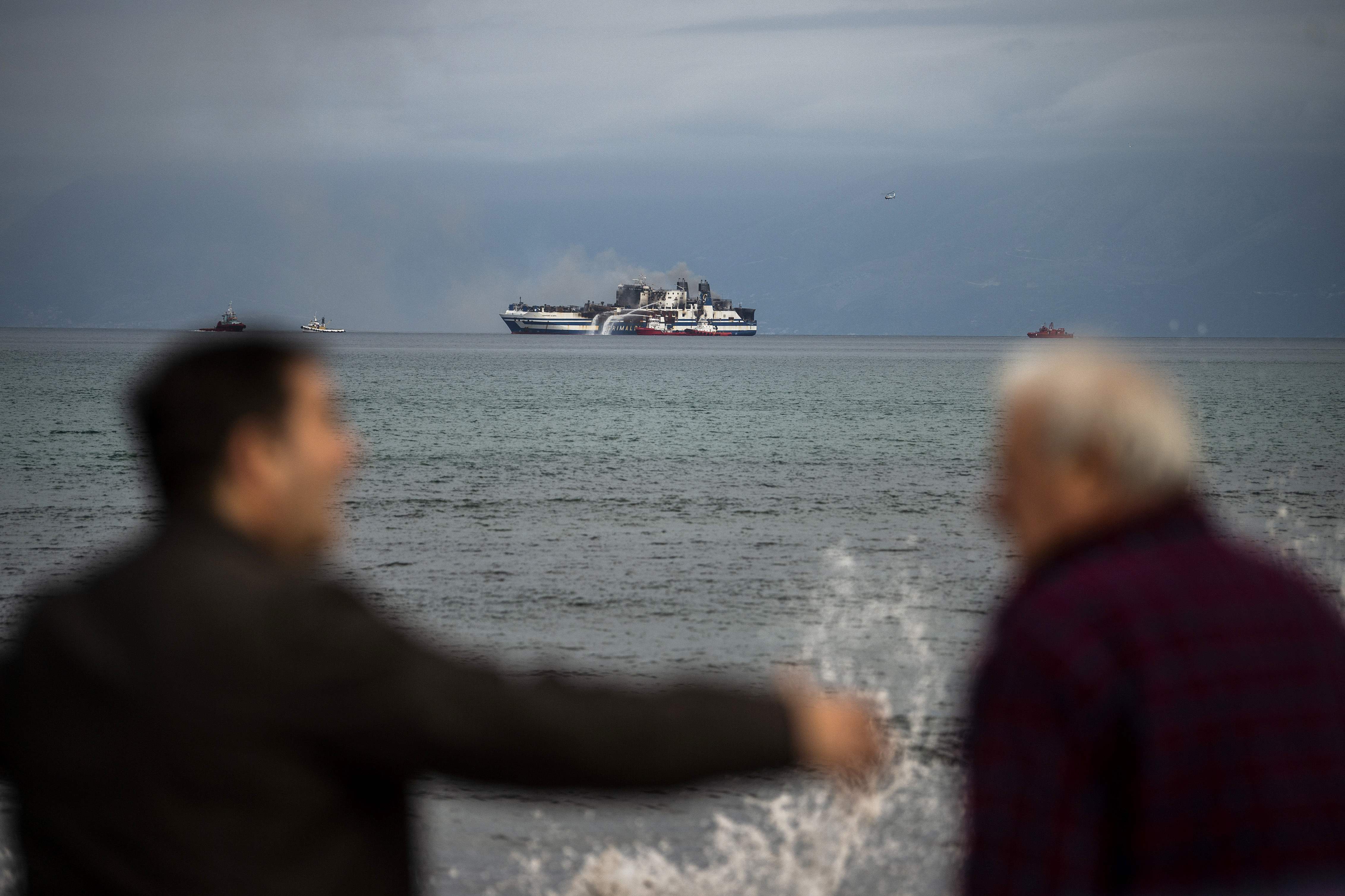 The stricken ferry can be seen in the background as smoke rises