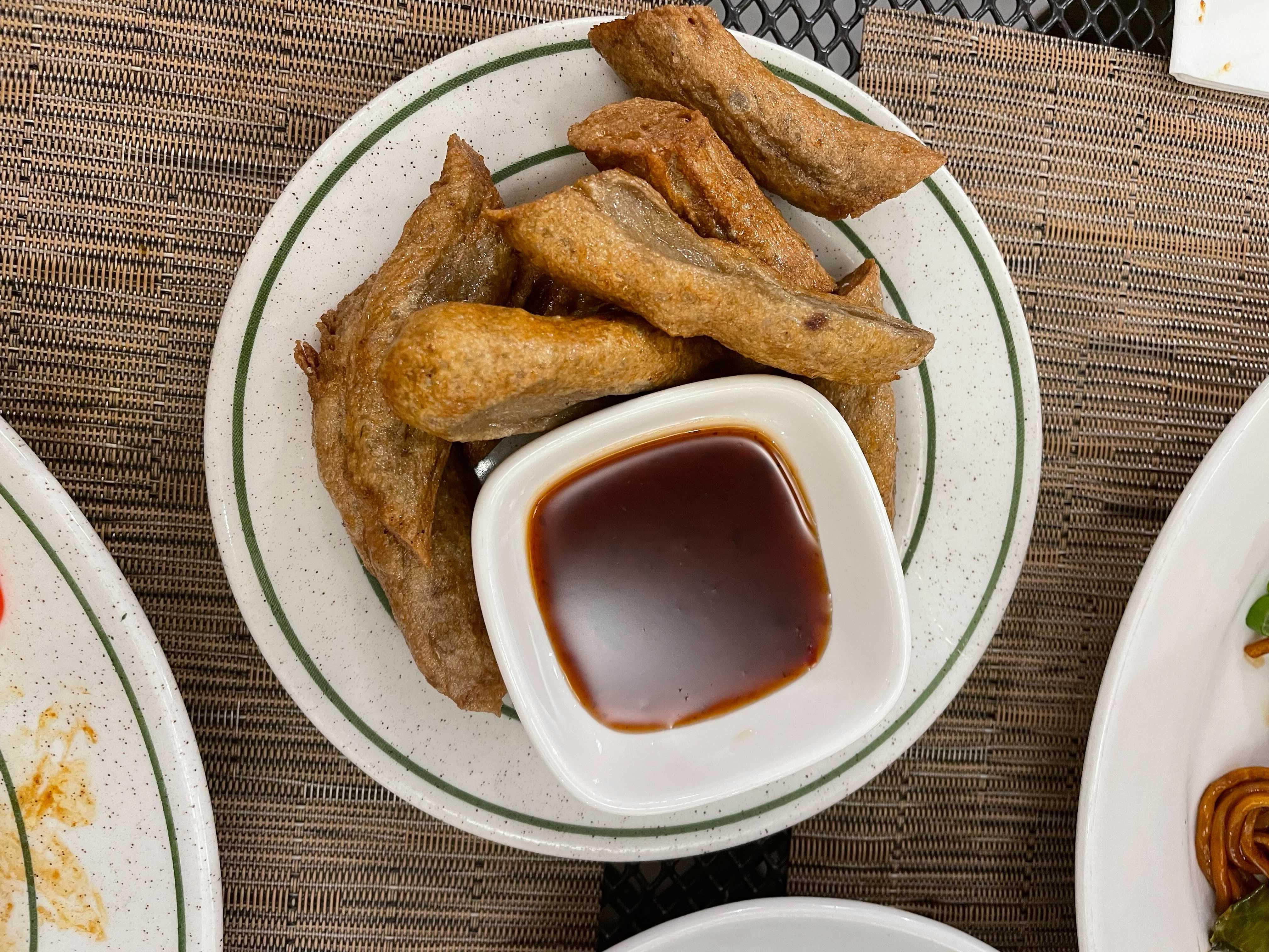 A plate of crunchy bites of deep-fried fish paste, known as keropok lekor, with a tangy, spicy dipping sauce