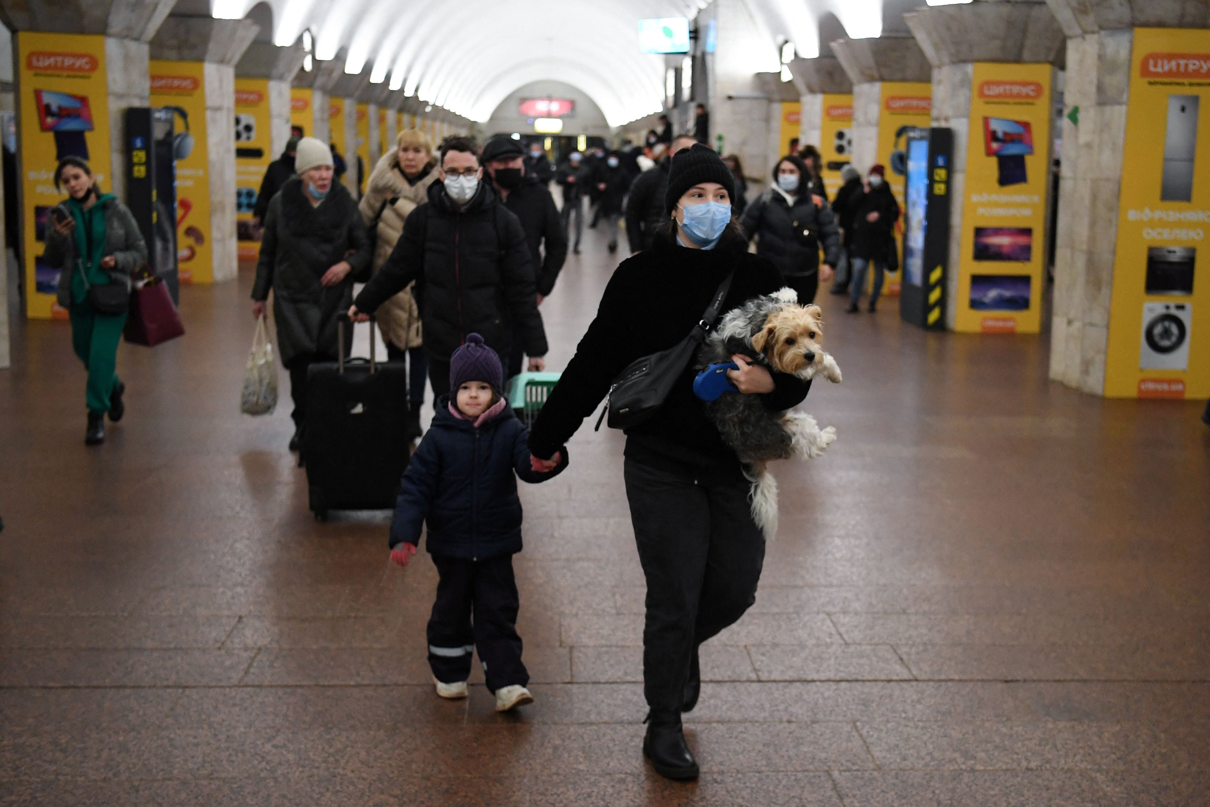 A woman with a child and a dog walks at a metro station in Kiev early on 24 February