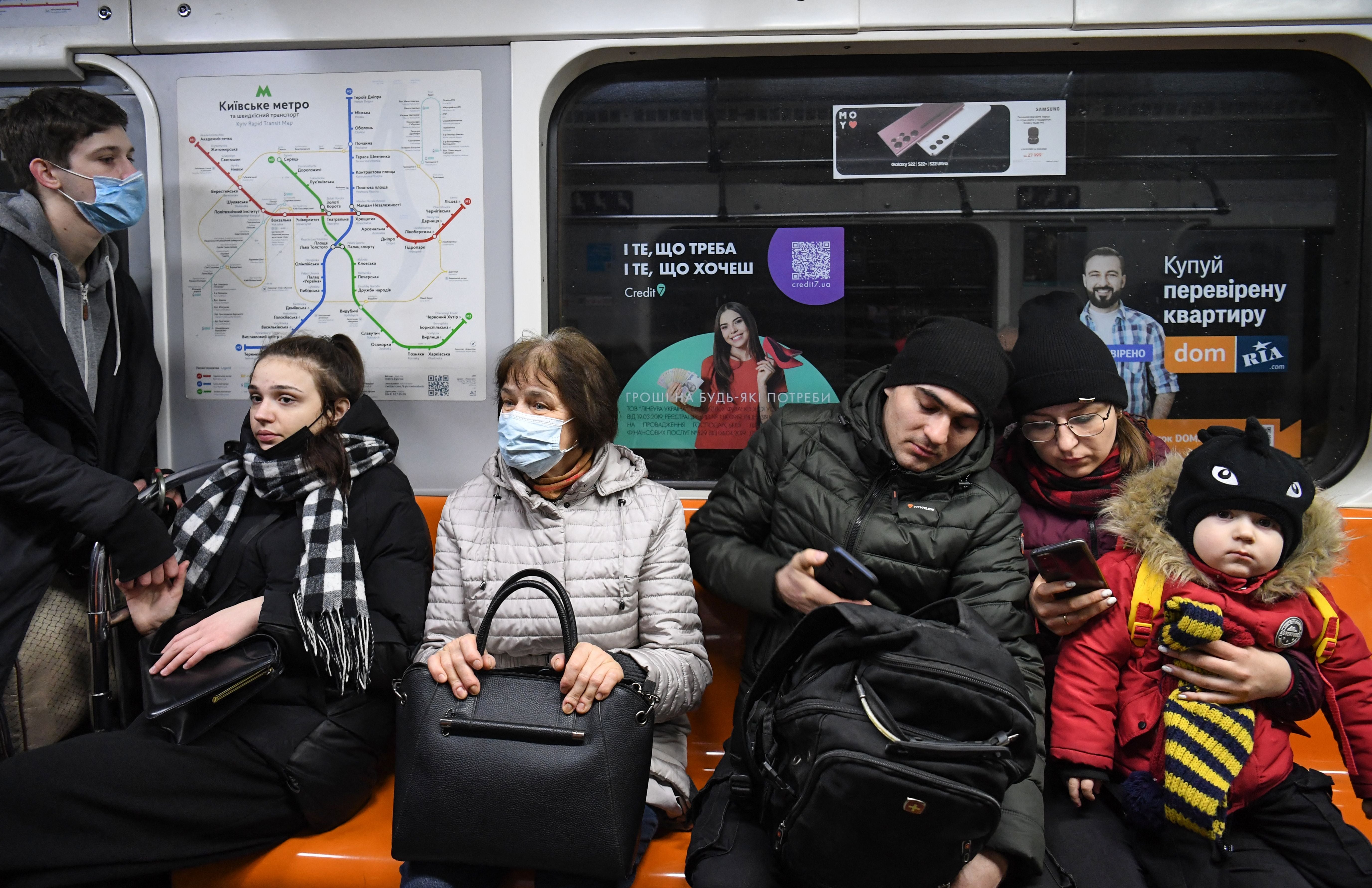 People, some carrying bags, sit in a metro in Kiev in the morning of 24 February