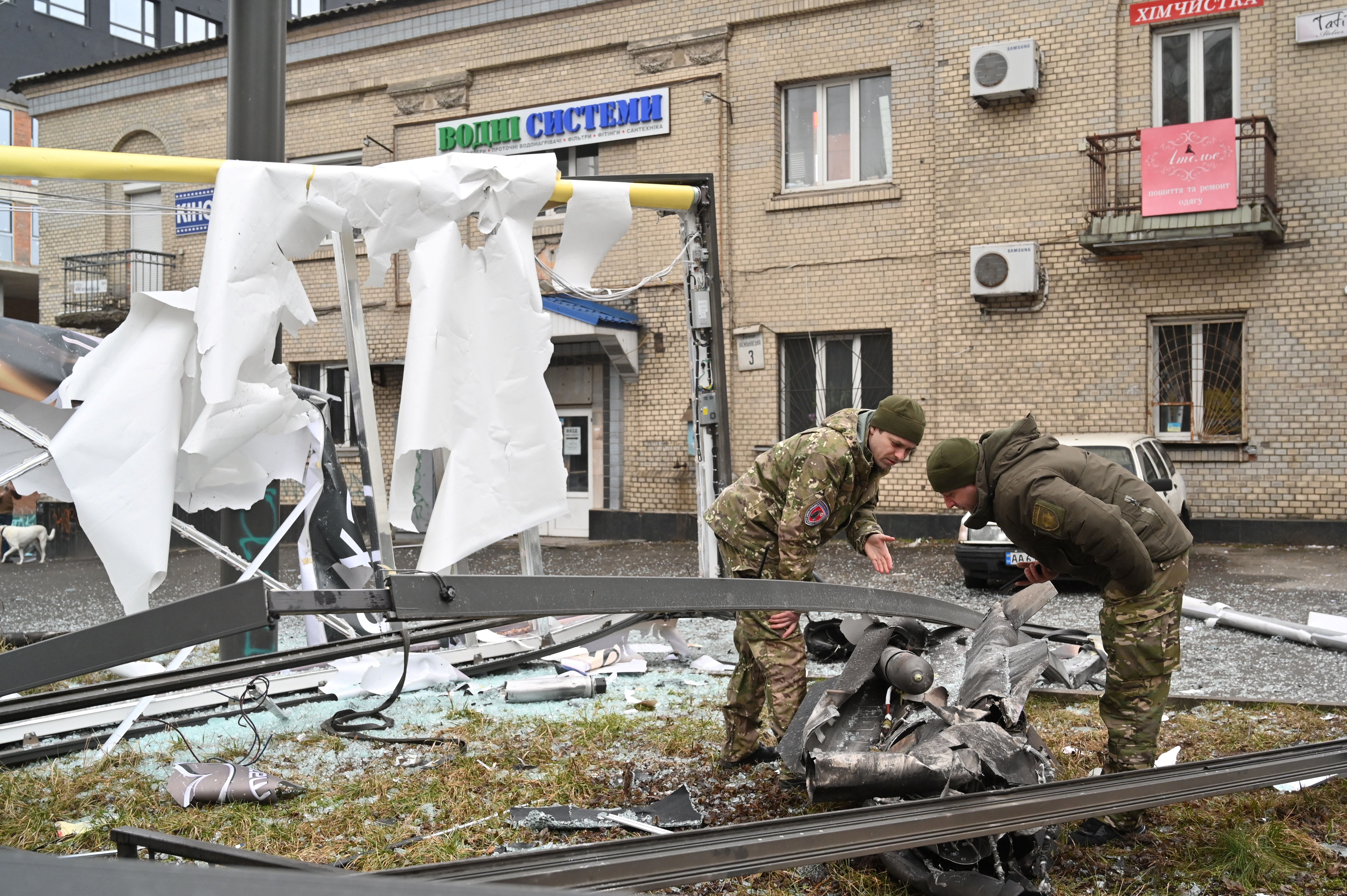 Police and security personnel inspect the remains of a shell in a street in Kiev