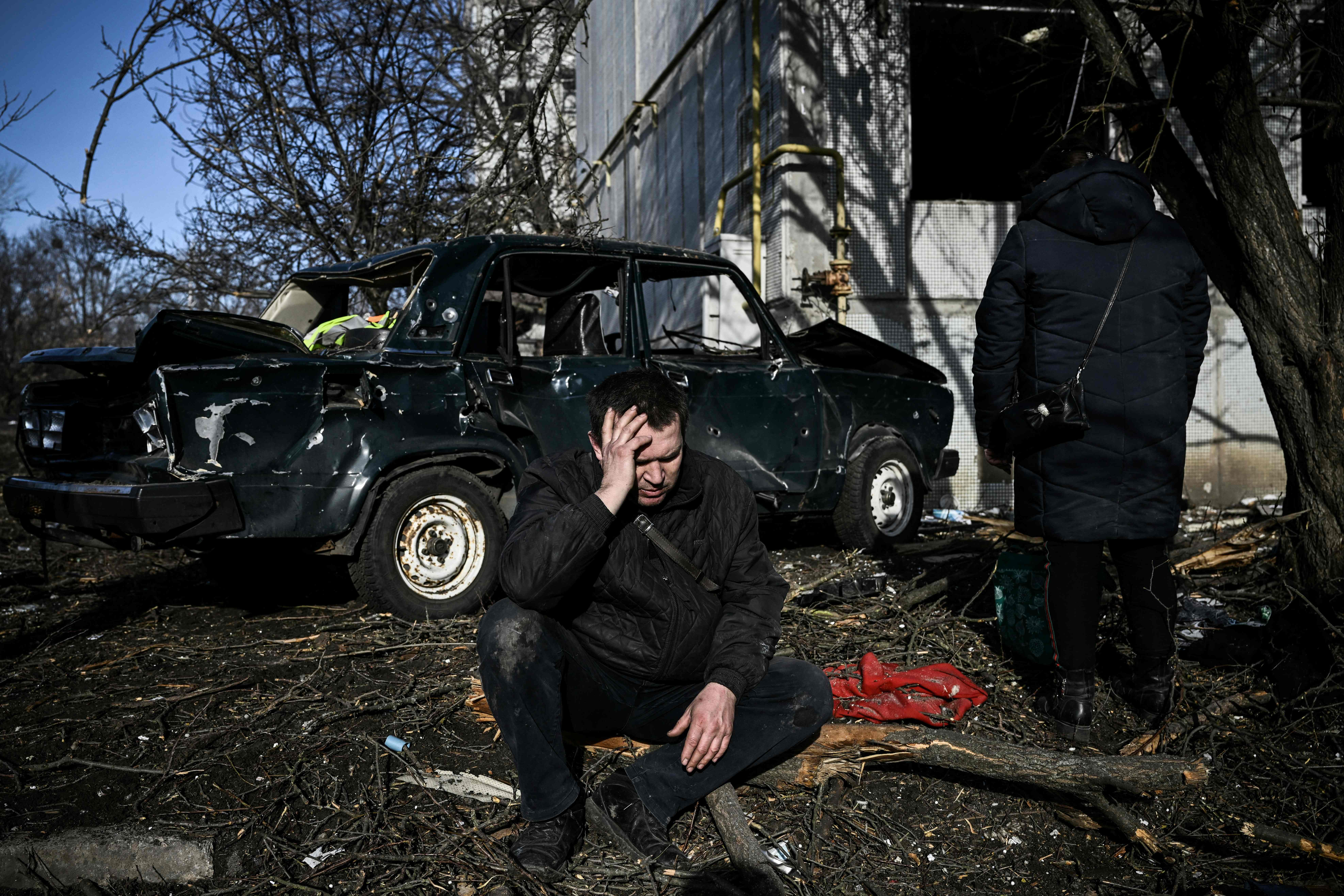 A man sits outside his destroyed building after bombings on the eastern Ukraine town of Chuguiv on 24 February 2022