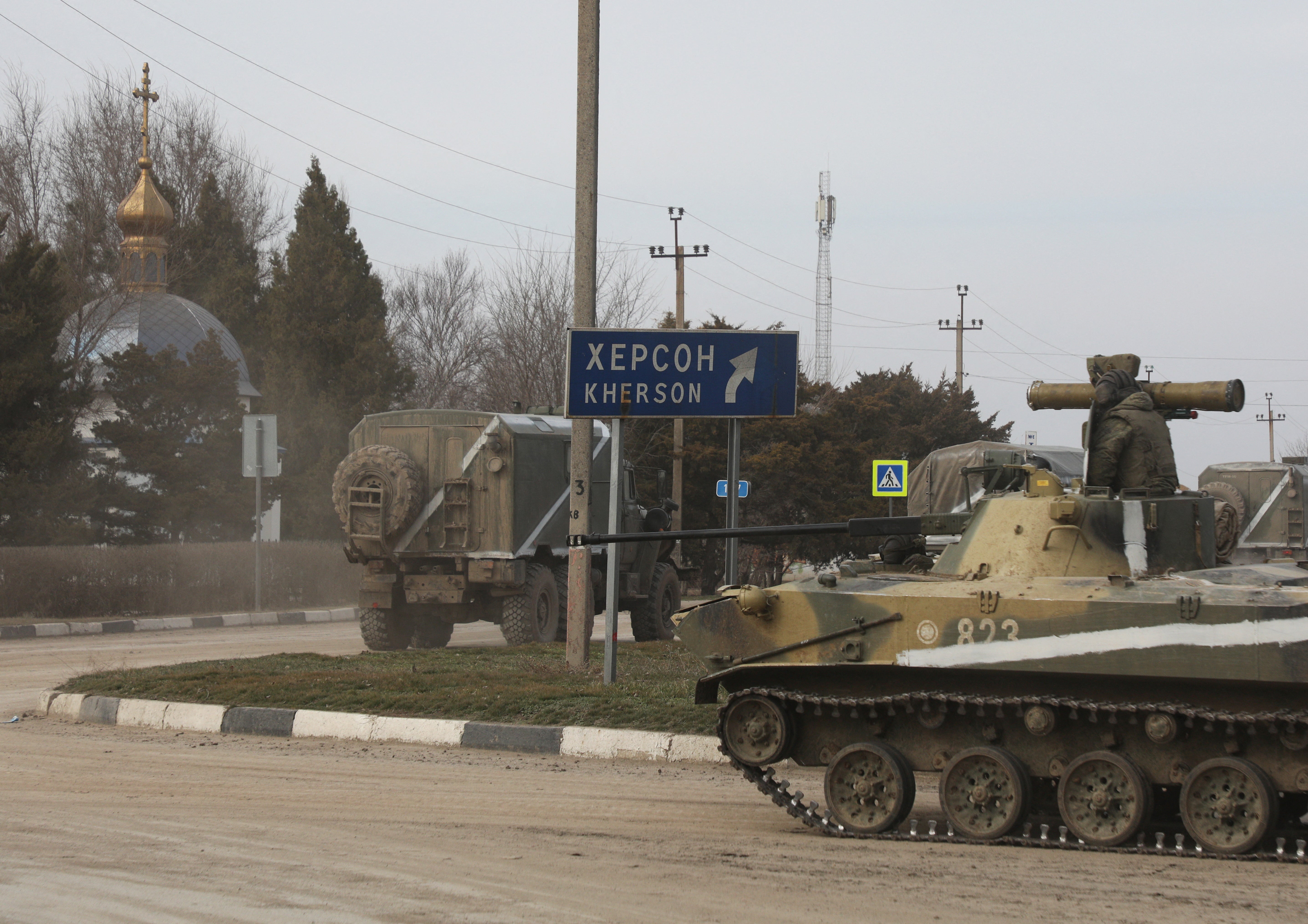 Military vehicles drive along a street, after Russian President Vladimir Putin authorized a military operation in eastern Ukraine, in the town of Armyansk