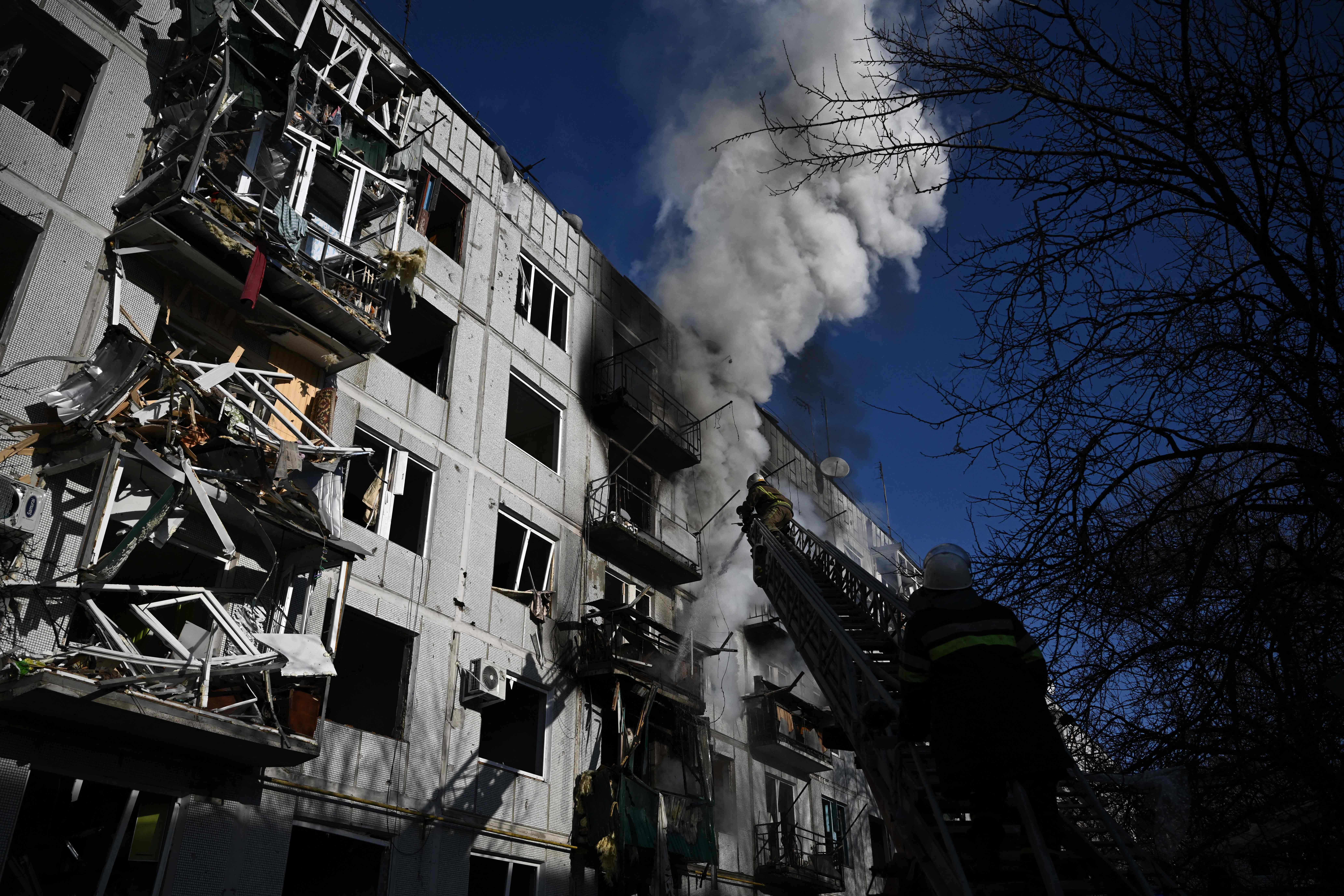 Firefighters work on a fire on a building after bombings on the eastern Ukraine town of Chuguiv on February 24, 2022, as Russian armed forces are trying to invade Ukraine from several directions, using rocket systems and helicopters to attack Ukrainian position in the south, the border guard service said