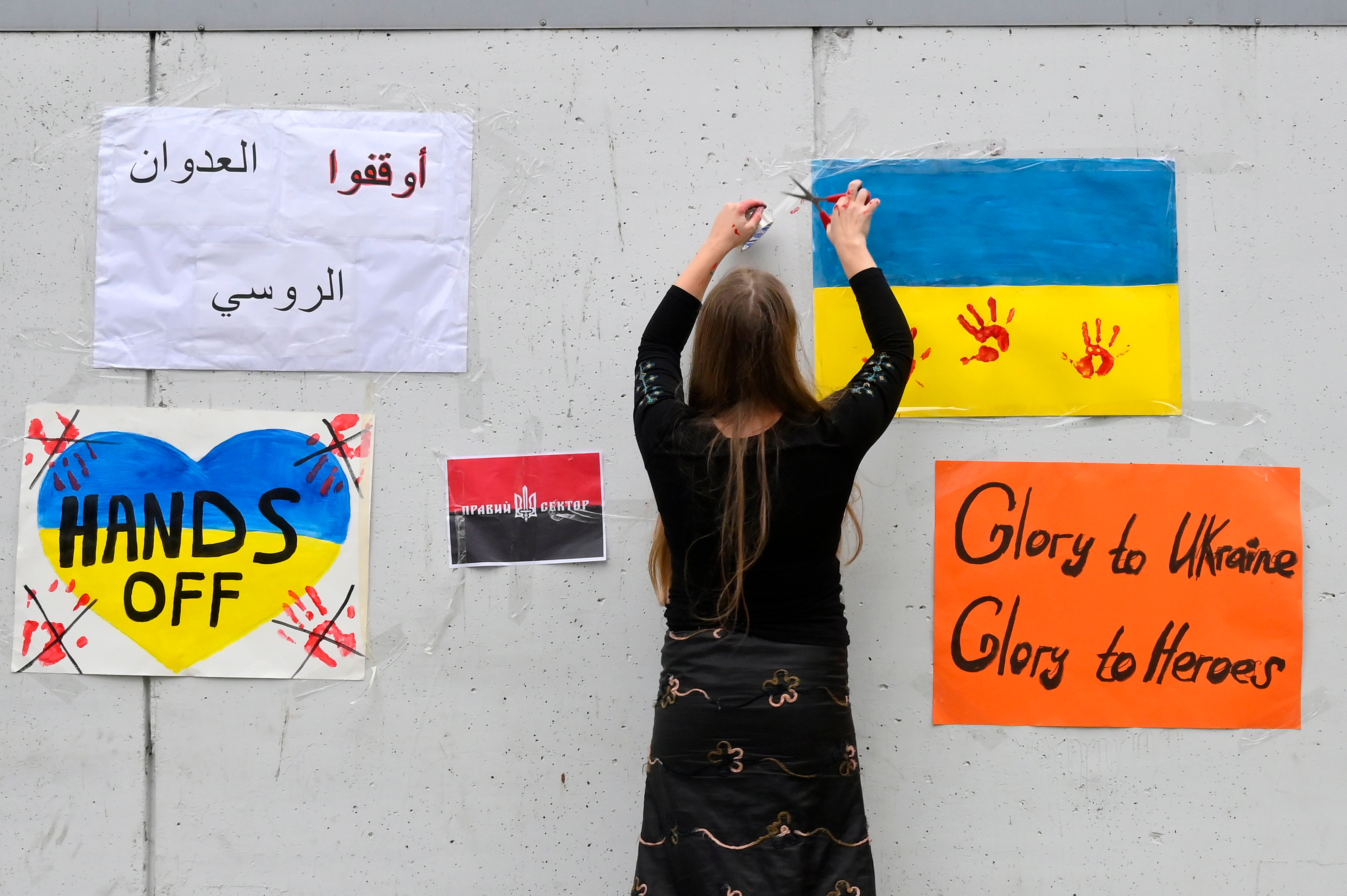 An Ukrainian woman who lives in Lebanon hangs a placard on a wall during a protest outside the Russian embassy in Beirut, Lebanon,