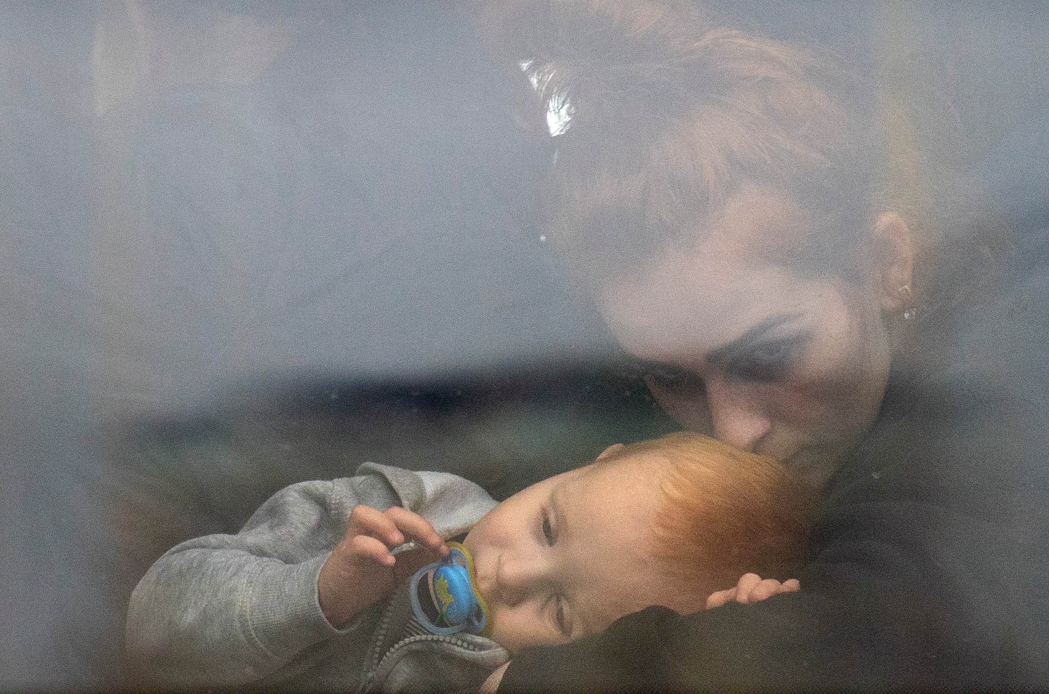 A woman holds her baby inside a bus as they leave Kyiv, Ukraine