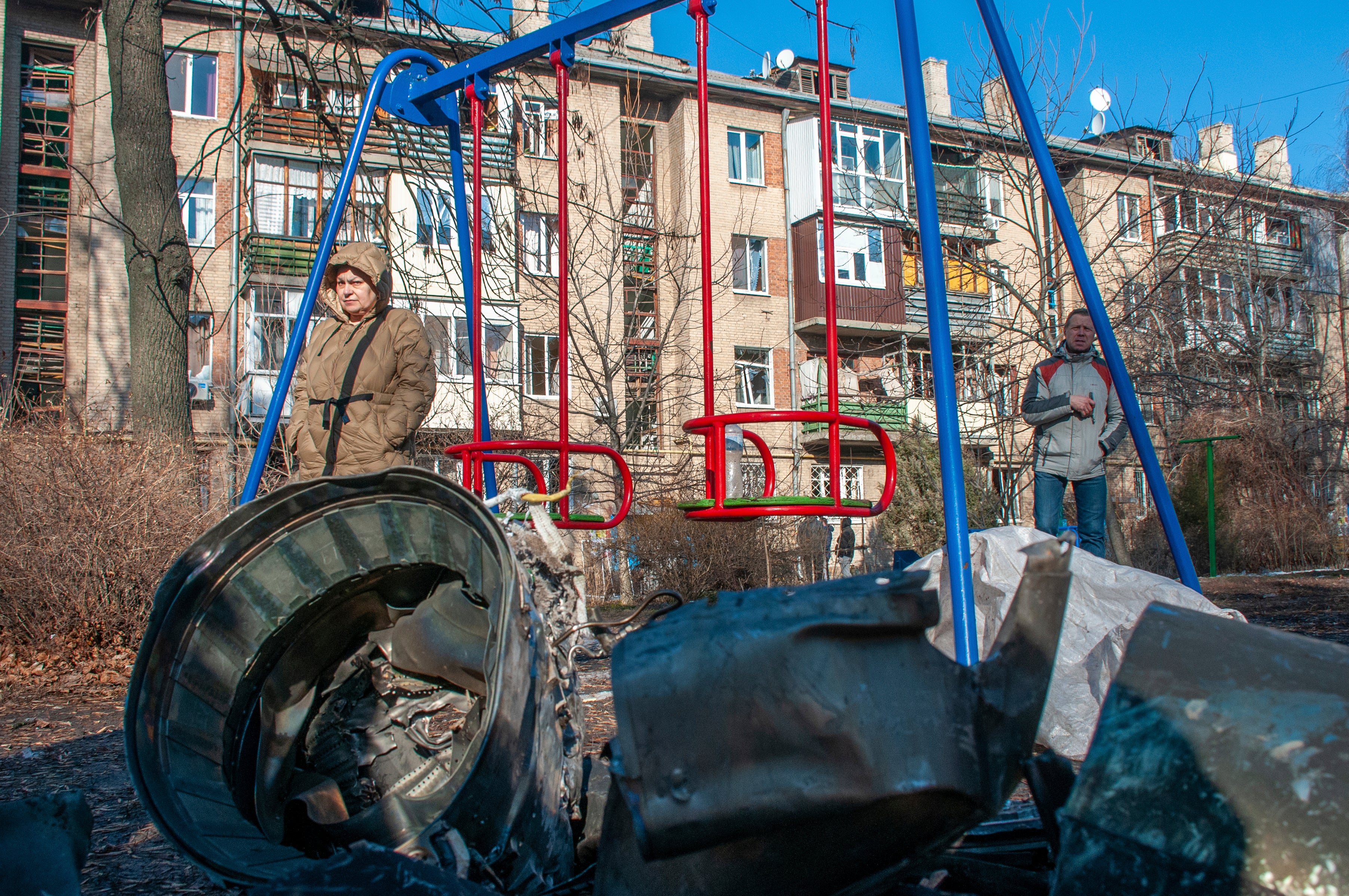 A man and woman stand next to fragments of military equipment in the aftermath of an apparent Russian strike in Kharkiv