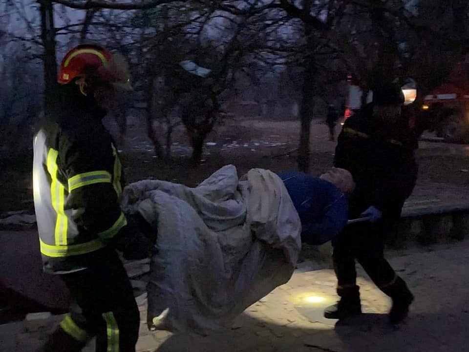 Rescuers help a local resident after shelling in the town of Starobilsk