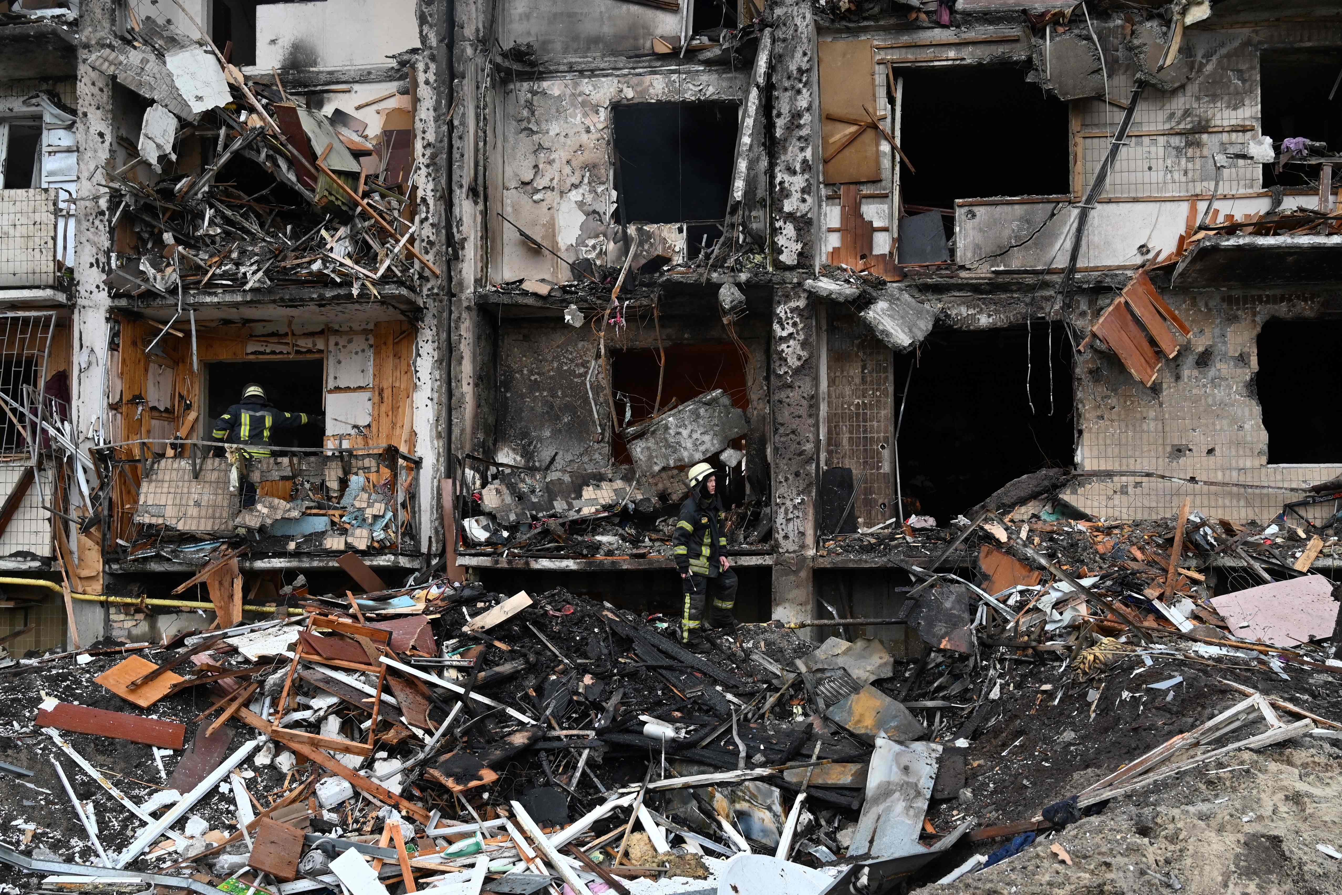 Firefighters work at a damaged residential building at Koshytsa Street, a suburb of the Ukrainian capital Kyiv, where a military shell allegedly hit, on 25 February 2022