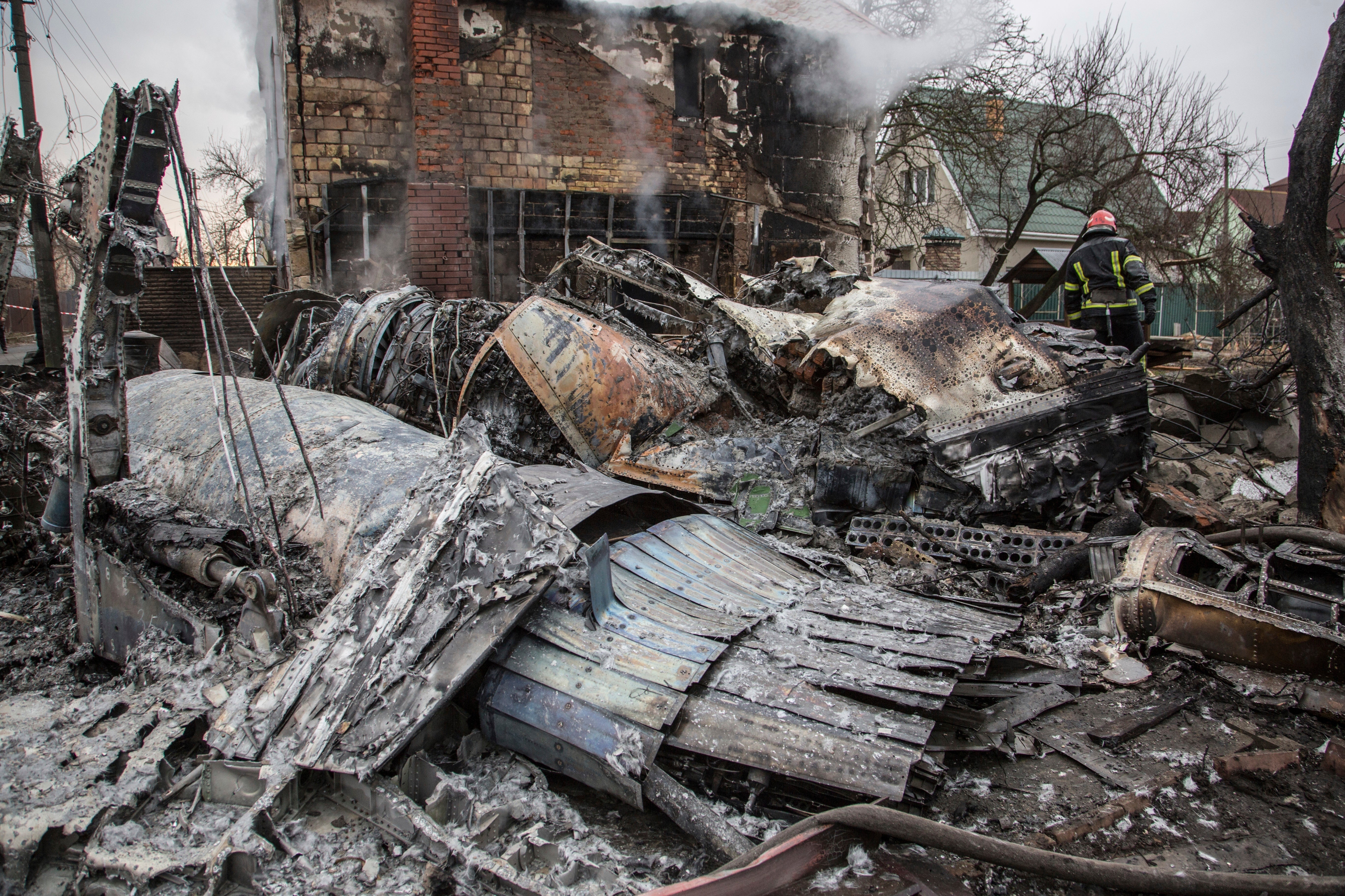 A Ukrainian firefighter walks between at fragments of a downed aircraft