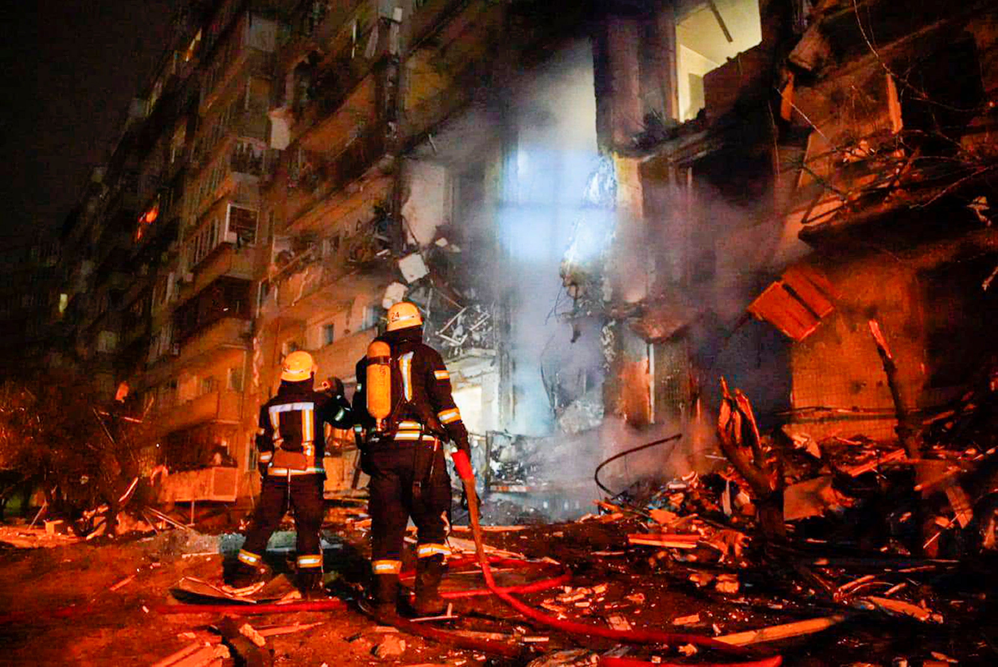 Firefighters inspect the damage at a building following a rocket attack on the city of Kyiv