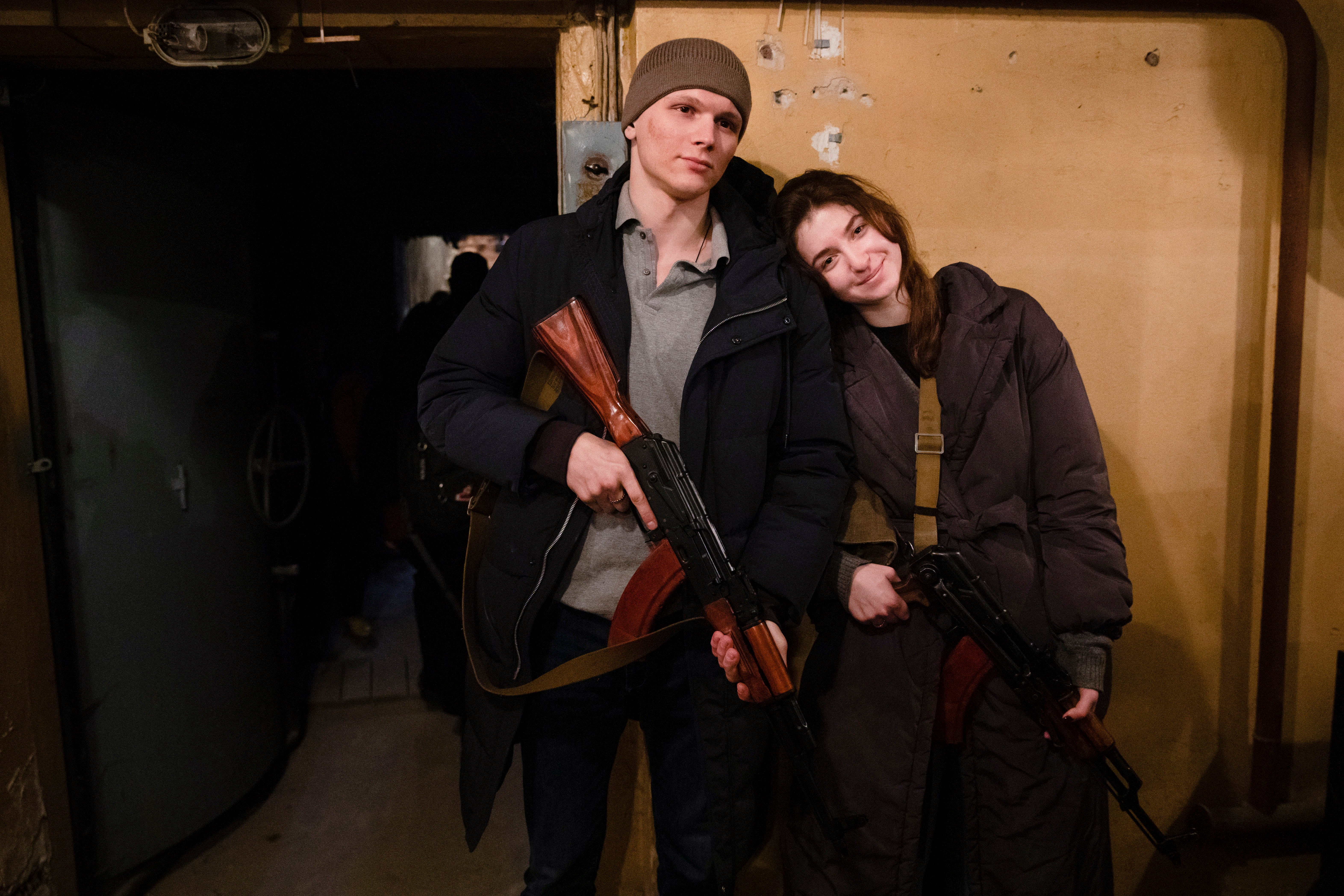 A young couple joining the territorial defence fighters smile after receiving weapons and ammunition in Kyiv