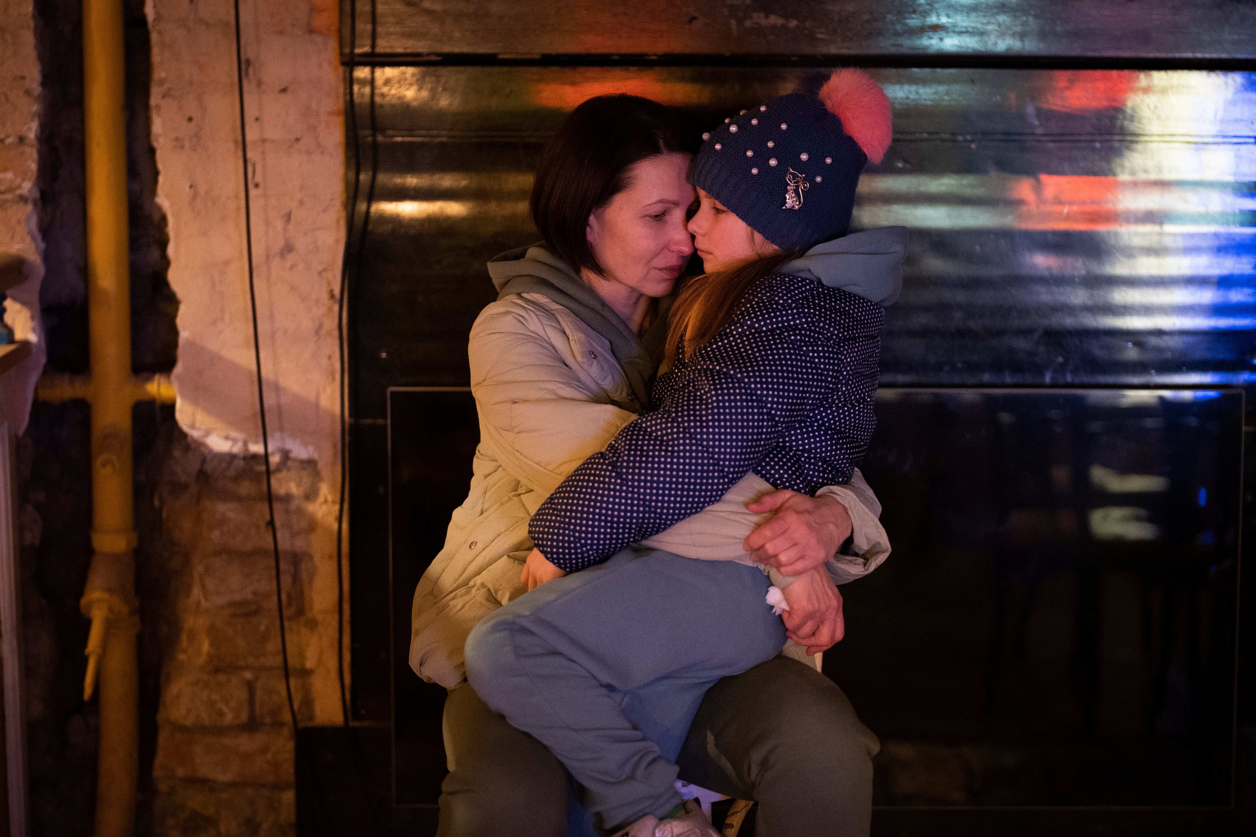 A woman holds her daughter as they sit in a basement used as a bomb shelter in Kyiv