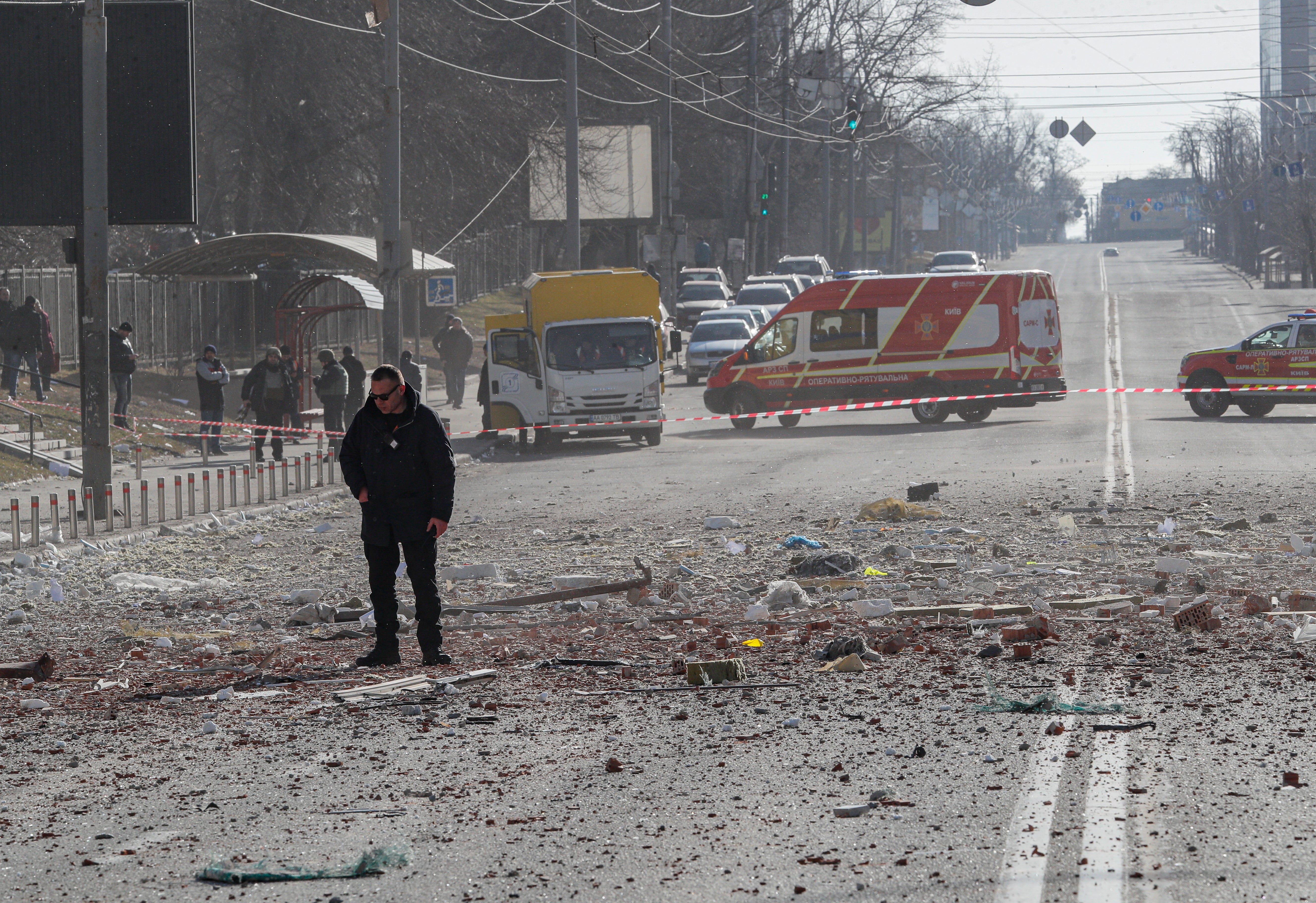 A man stands on the road near a high-rise apartment block which was hit by shelling in Kyiv