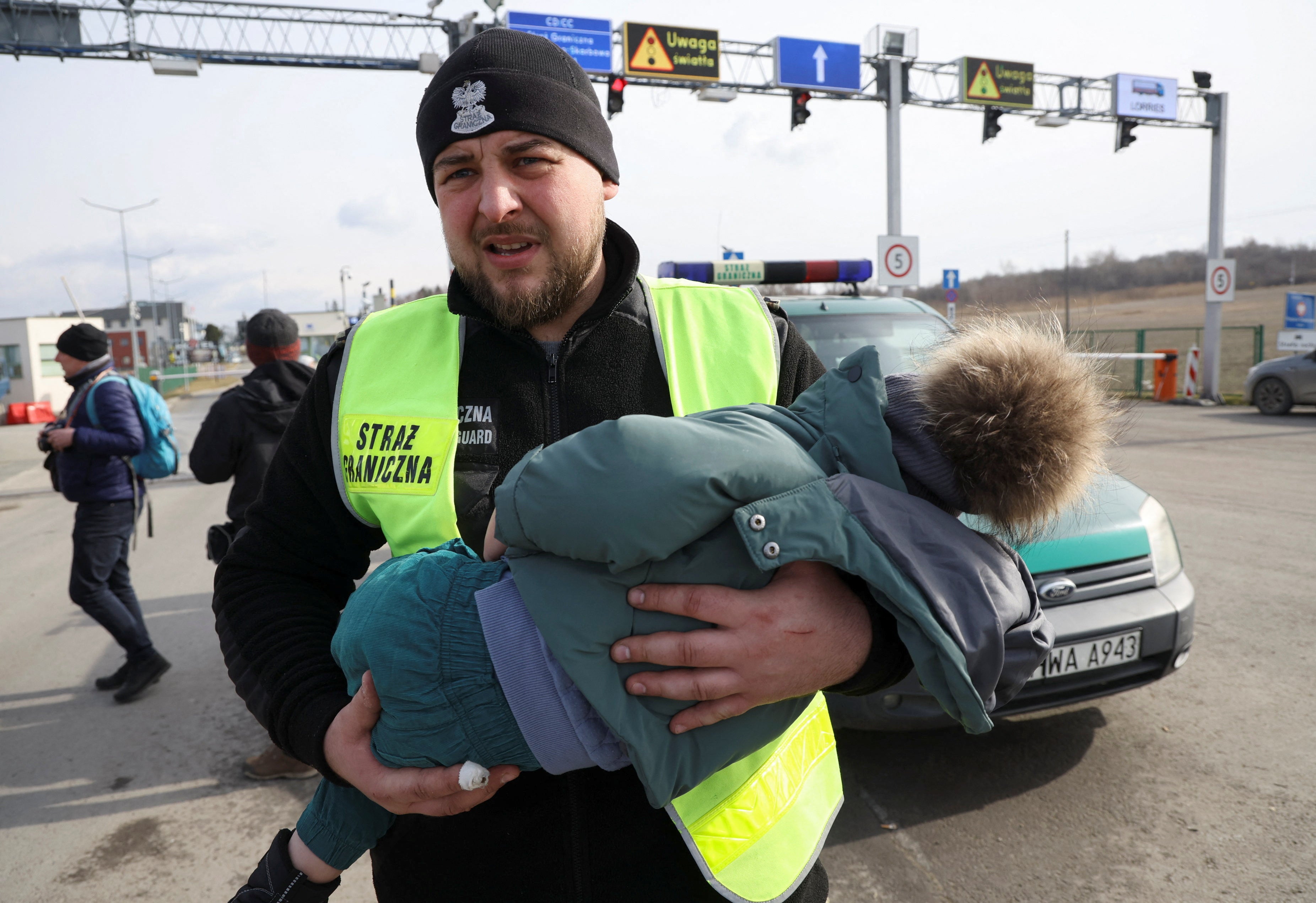 A Polish Border Guard carries a child near the border crossing between Poland and Ukraine on 26 February 2022