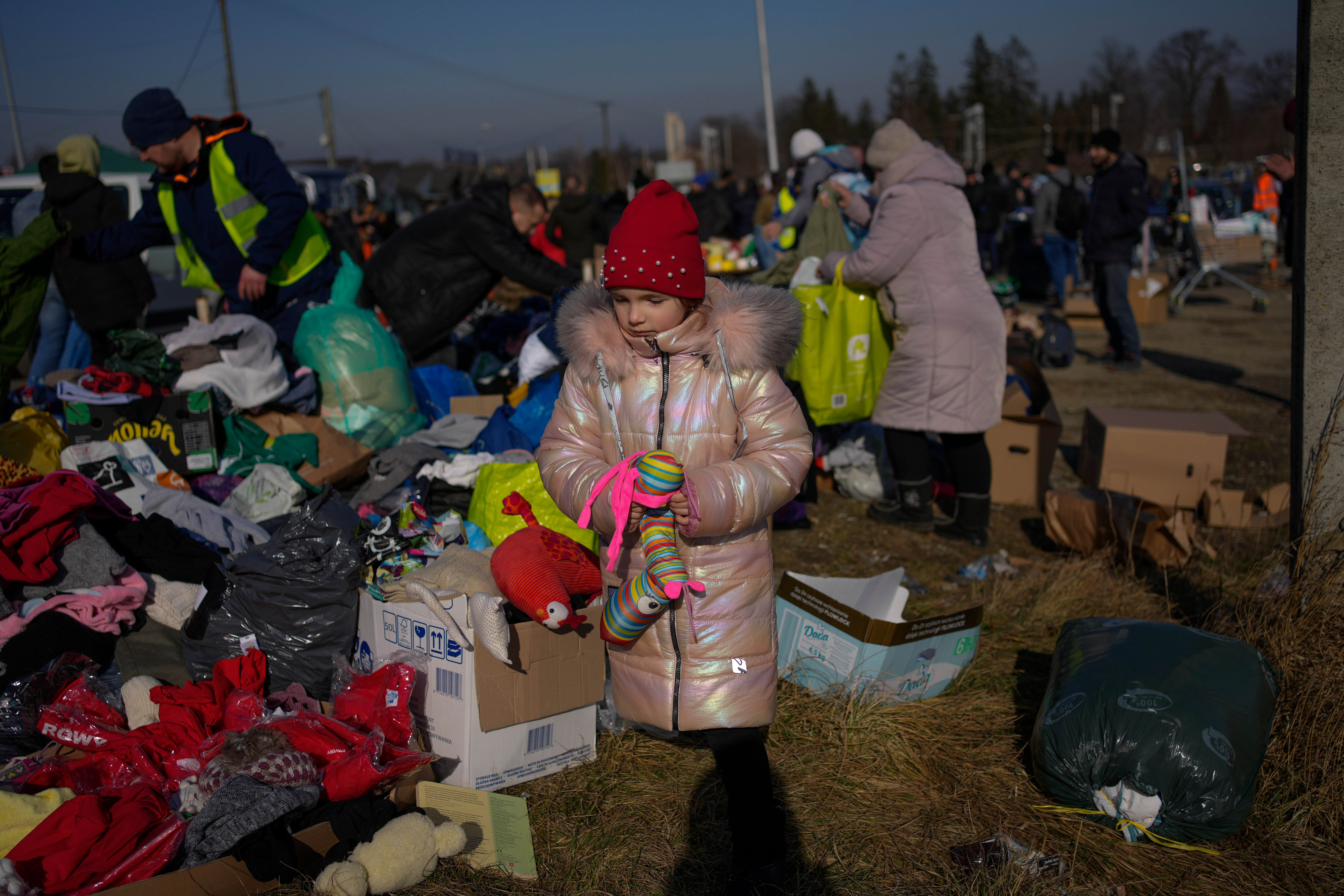 A Ukrainian refugee girl collects a toy from a pile of donated clothes at the Medyka border crossing, in Medyka, Poland