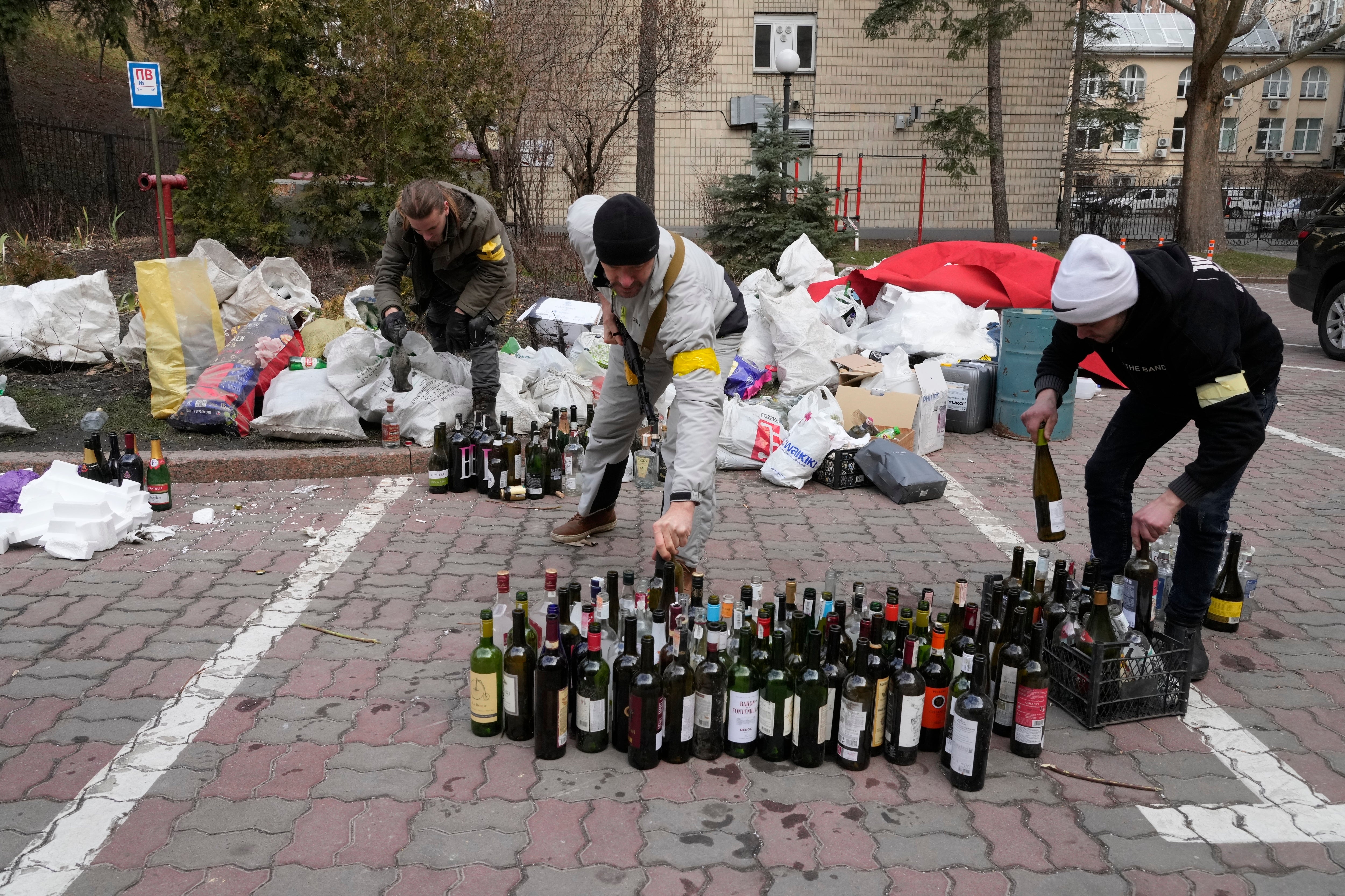 Members of civil defence prepare Molotov cocktails in a yard in Kyiv