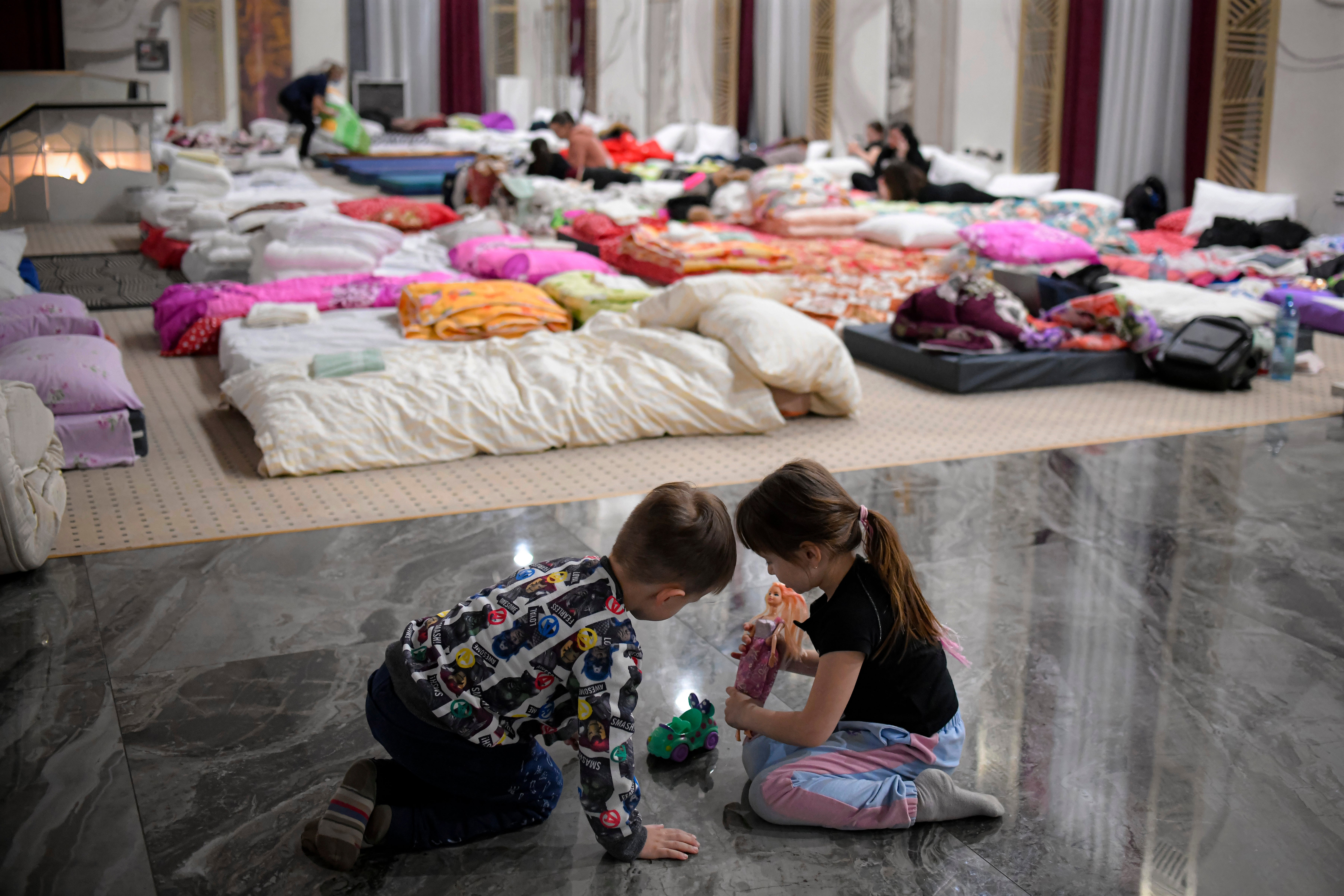 Children who fled the conflict from neighboring Ukraine play on the floor of an event hall in a hotel offering shelter in Siret, Romania